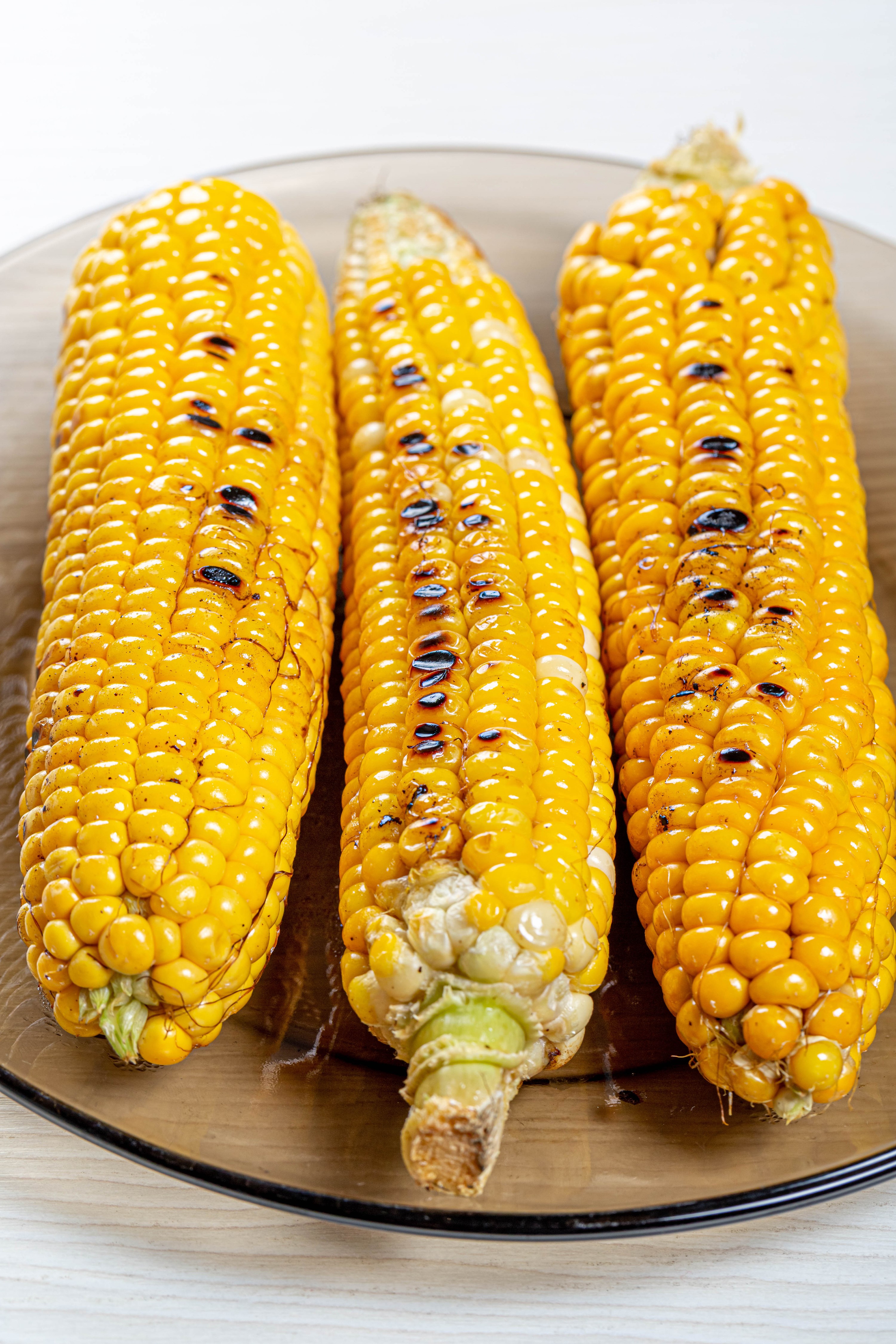 Three grilled corn on the cob on a plate HD Phone Wallpaper