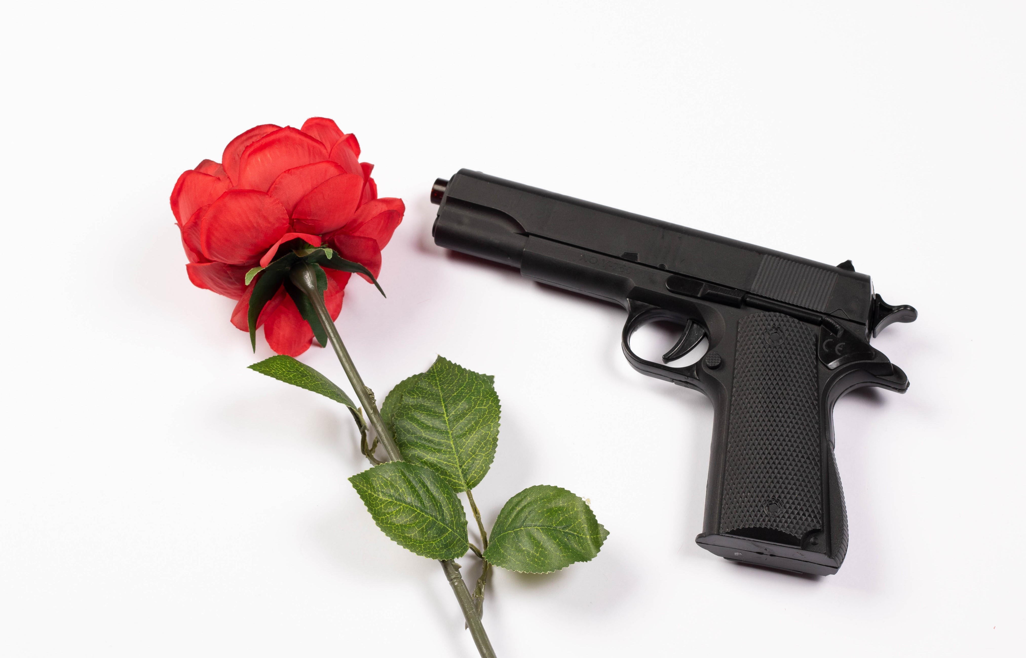 Red rose and black pistol on white background HD Wallpaper