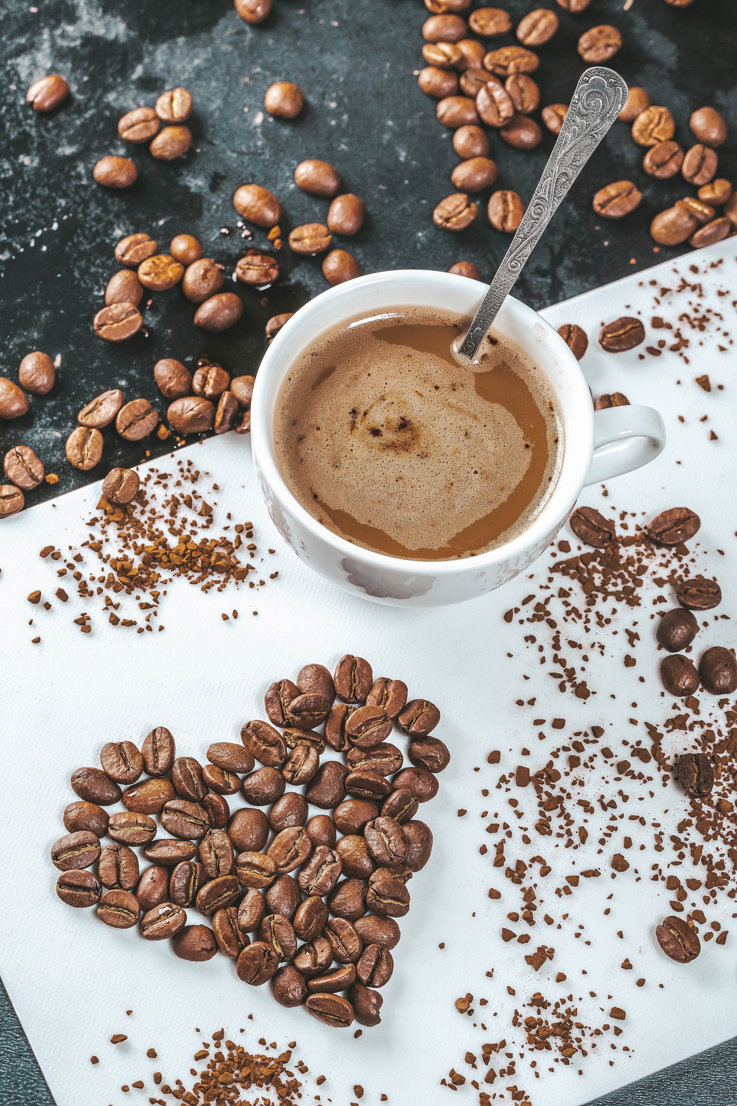 Coffee beans arranged in a heart shape next to a cup of coffee HD Phone Wallpaper