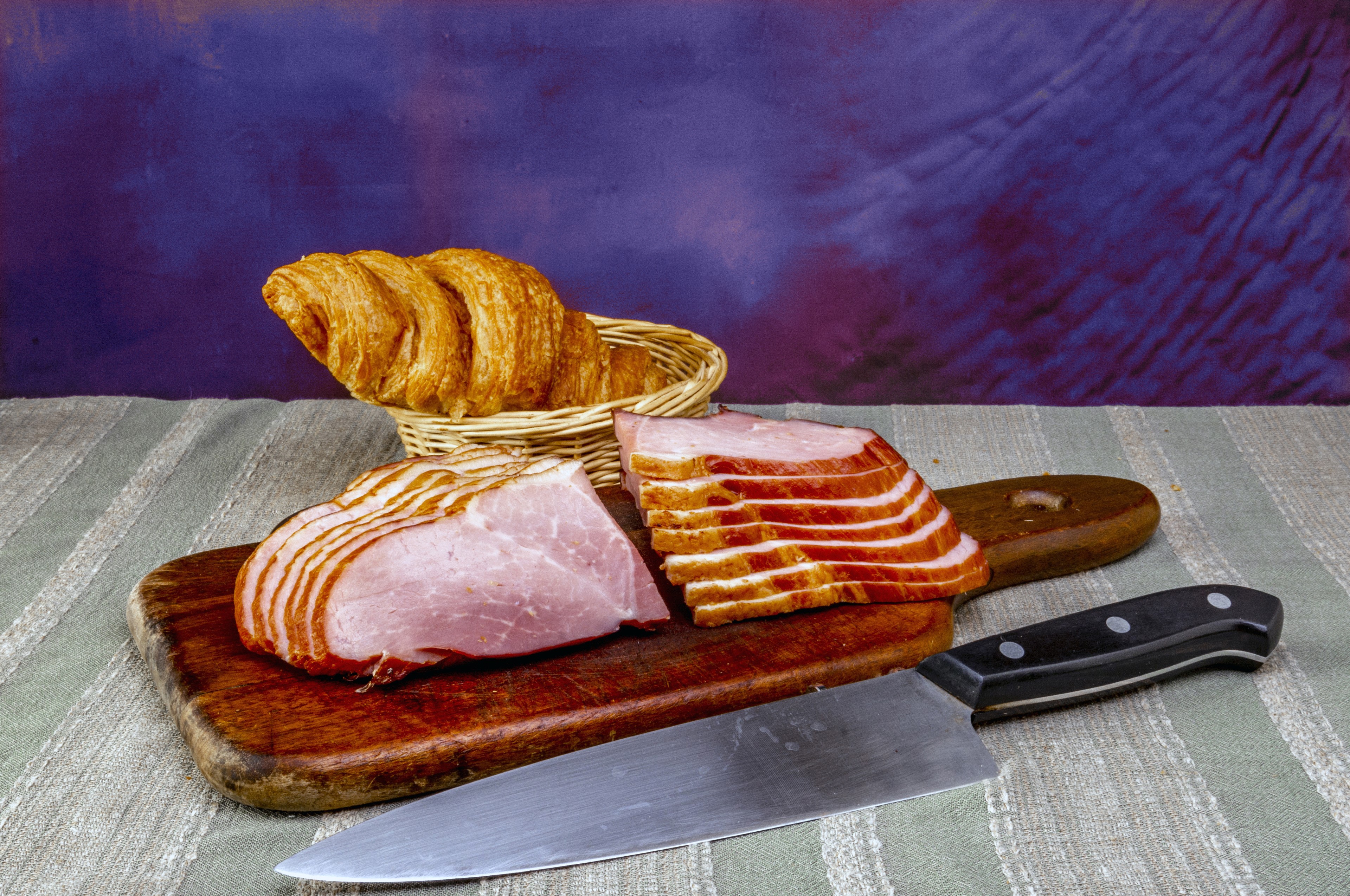 Ham slices and croissant on cutting board with knife HD Wallpaper