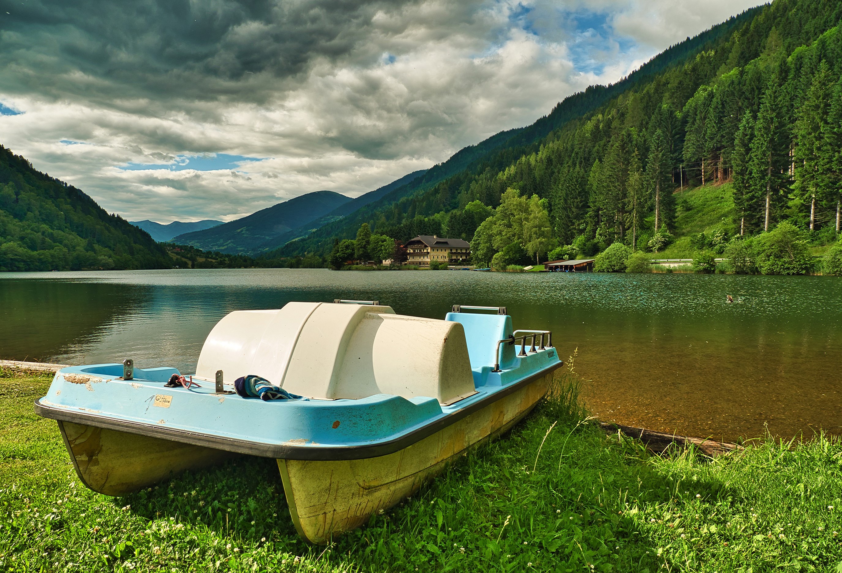 Pedal boat on the shore of a mountain lake in Austria HD Wallpaper