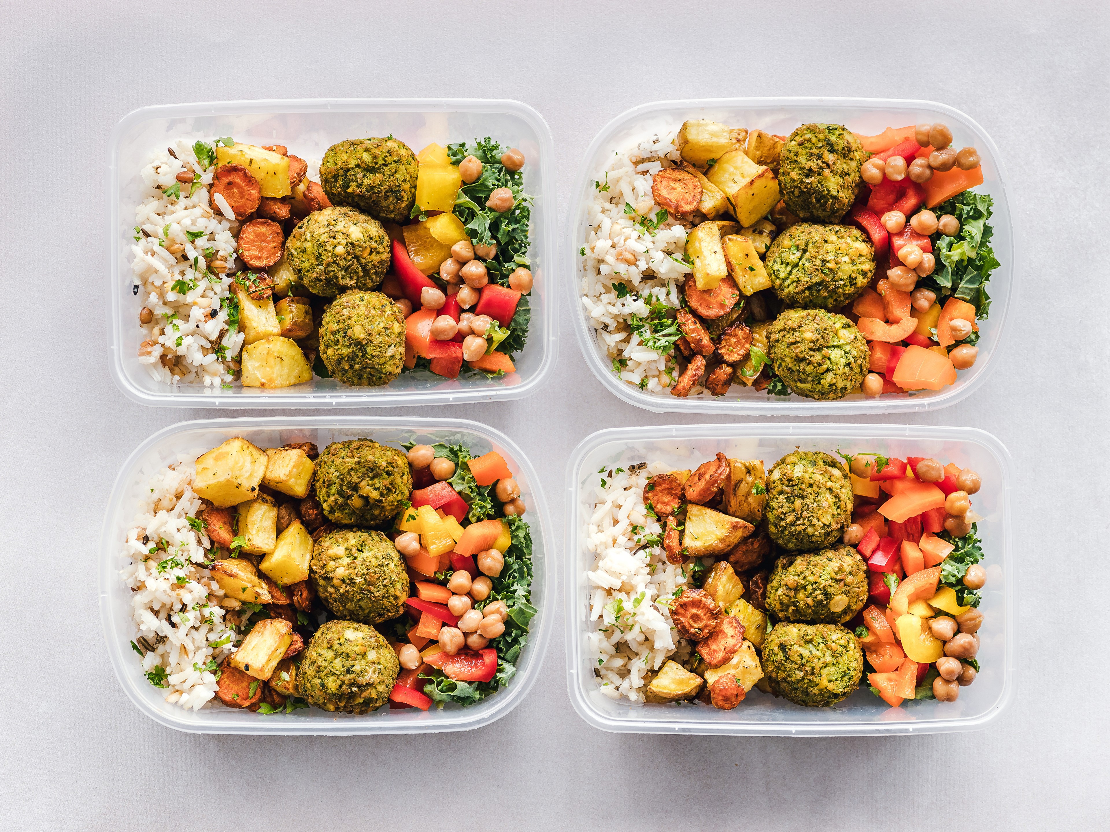 Four meal prep containers with falafel, rice, and vegetables HD Wallpaper