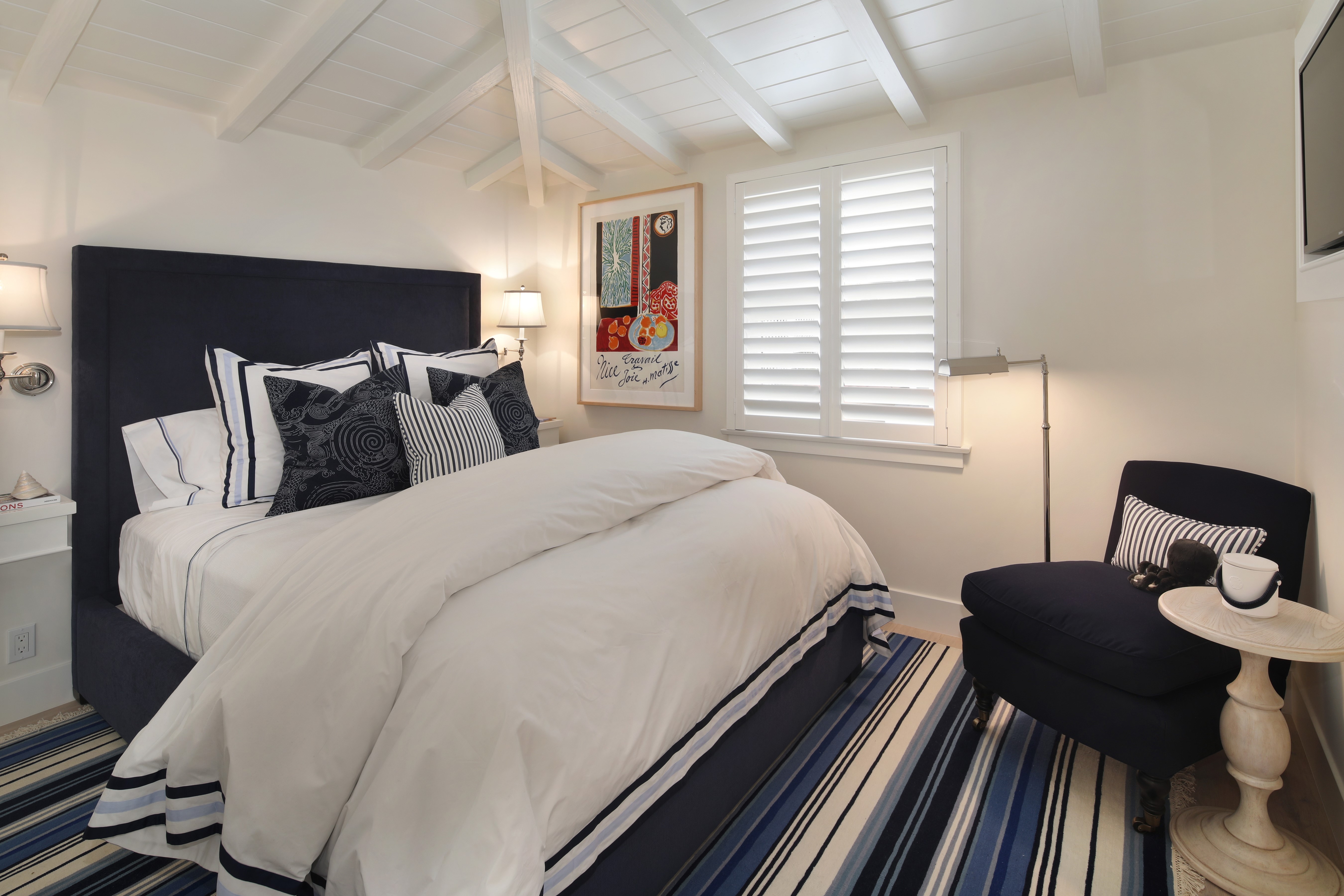 Bedroom with a bed, armchair, and striped rug HD Wallpaper