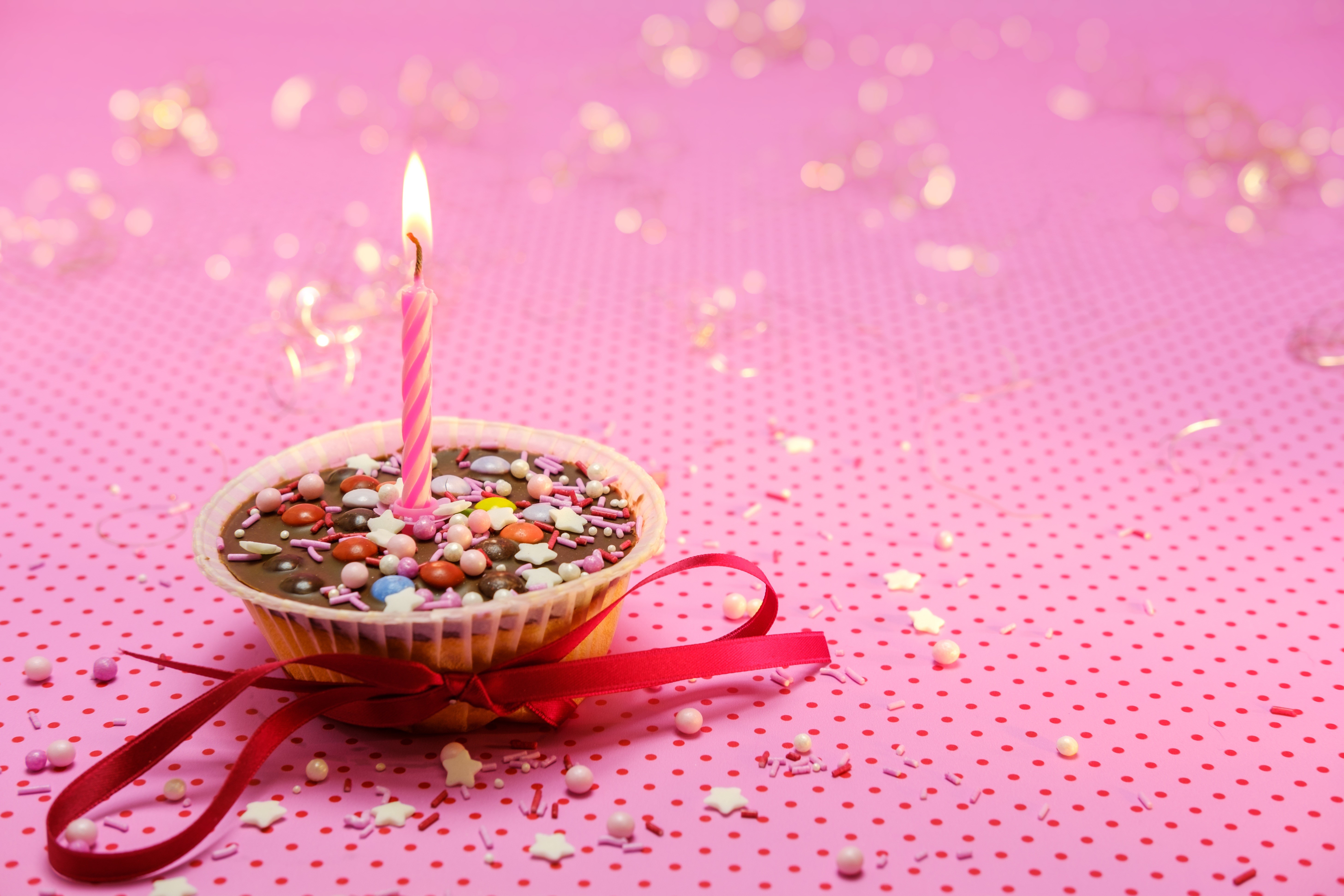 Birthday cupcake with lit candle and red ribbon HD Wallpaper
