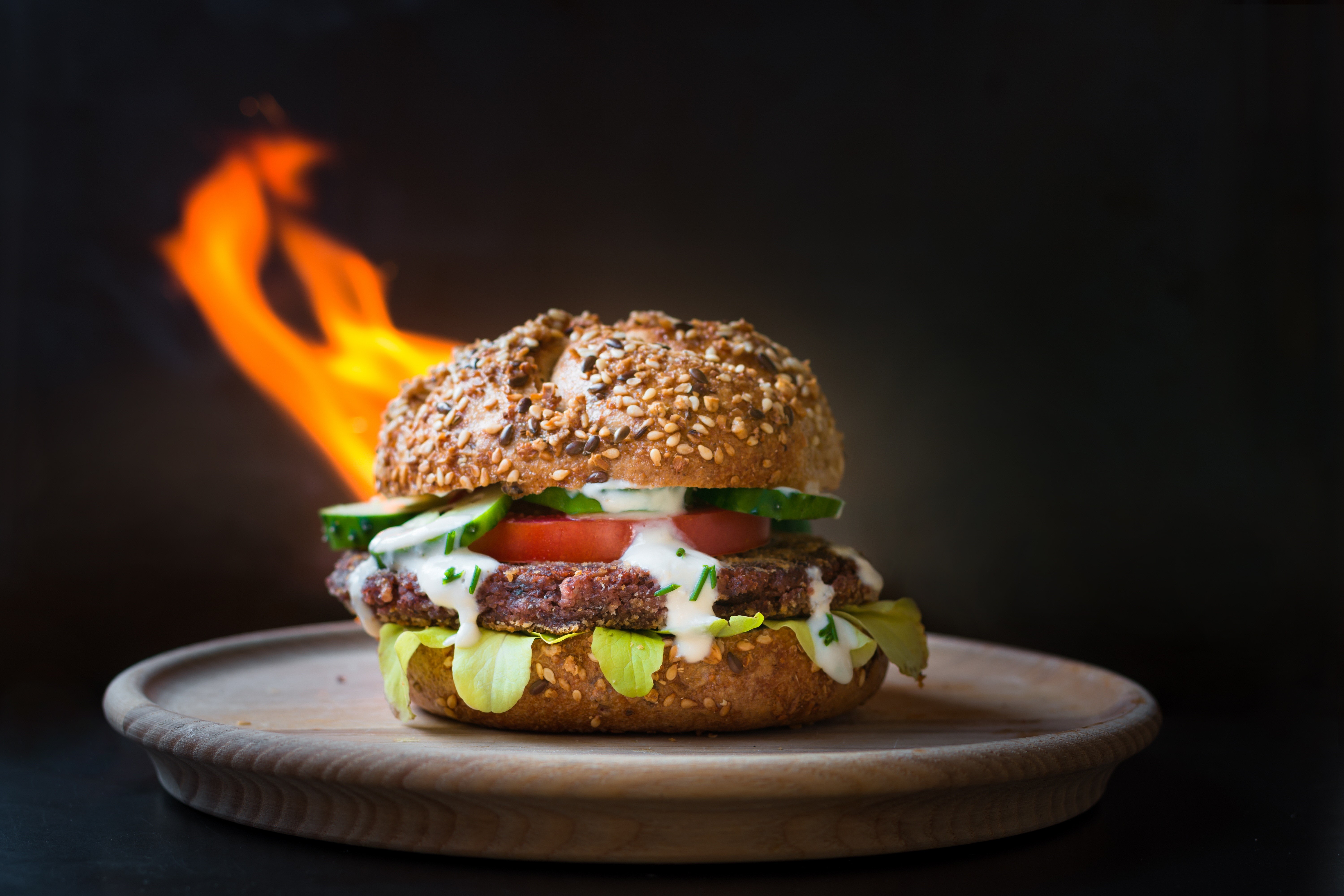 Hamburger with flames on a wooden plate HD Wallpaper