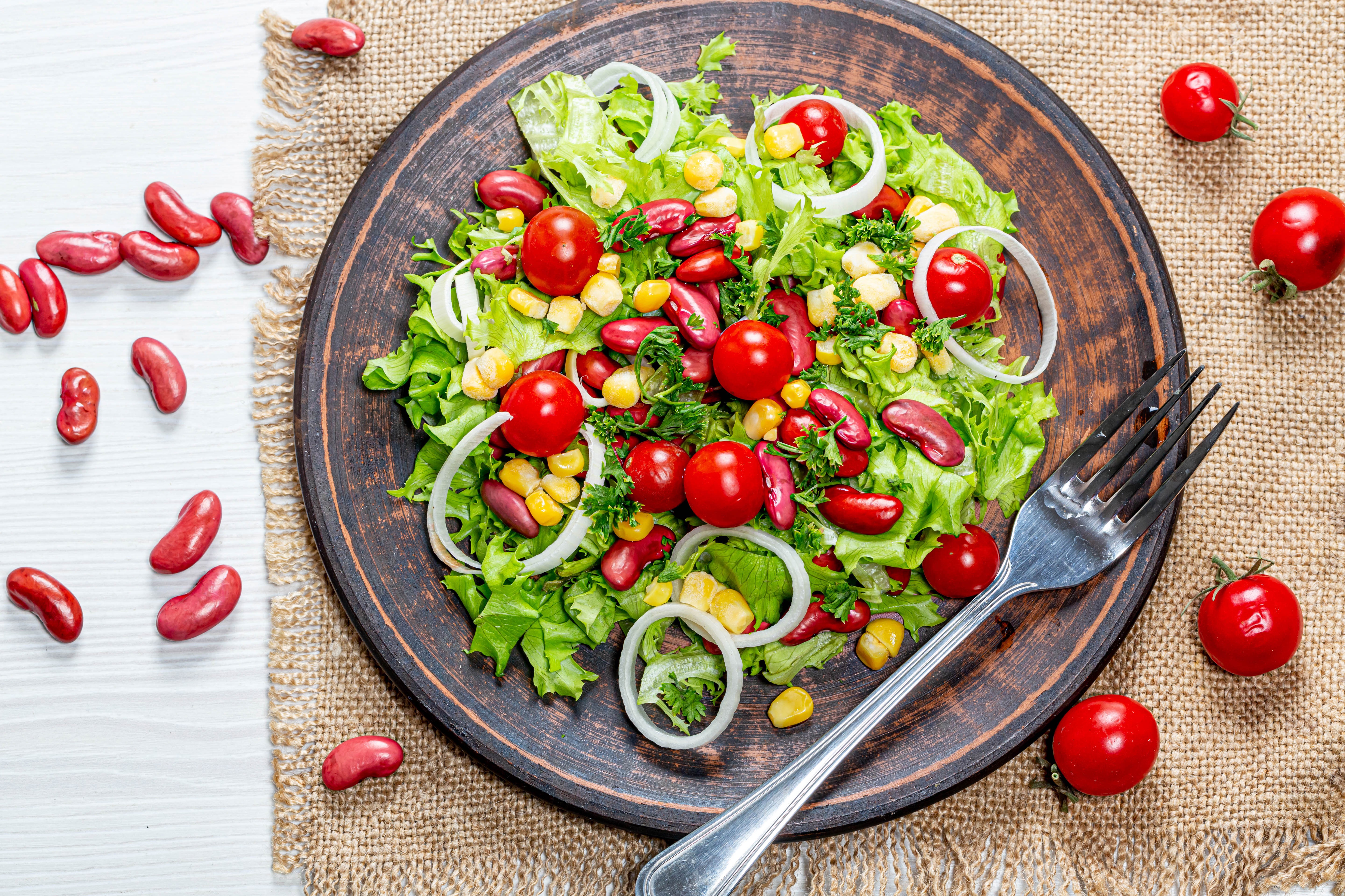 Salad with kidney beans, corn, tomatoes, and onion on a plate HD Wallpaper