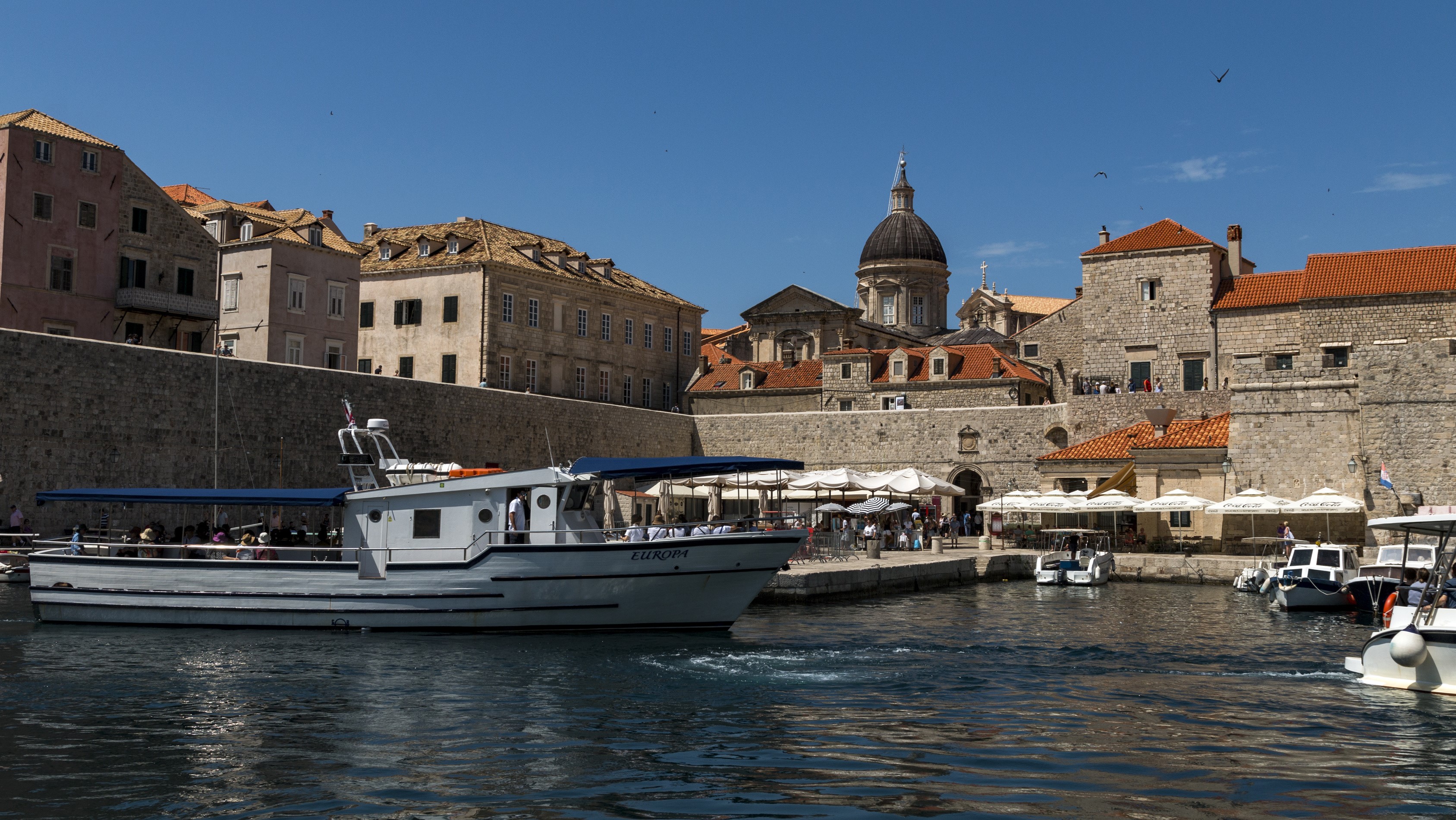 Boat in Dubrovnik harbor with historic buildings HD Wallpaper