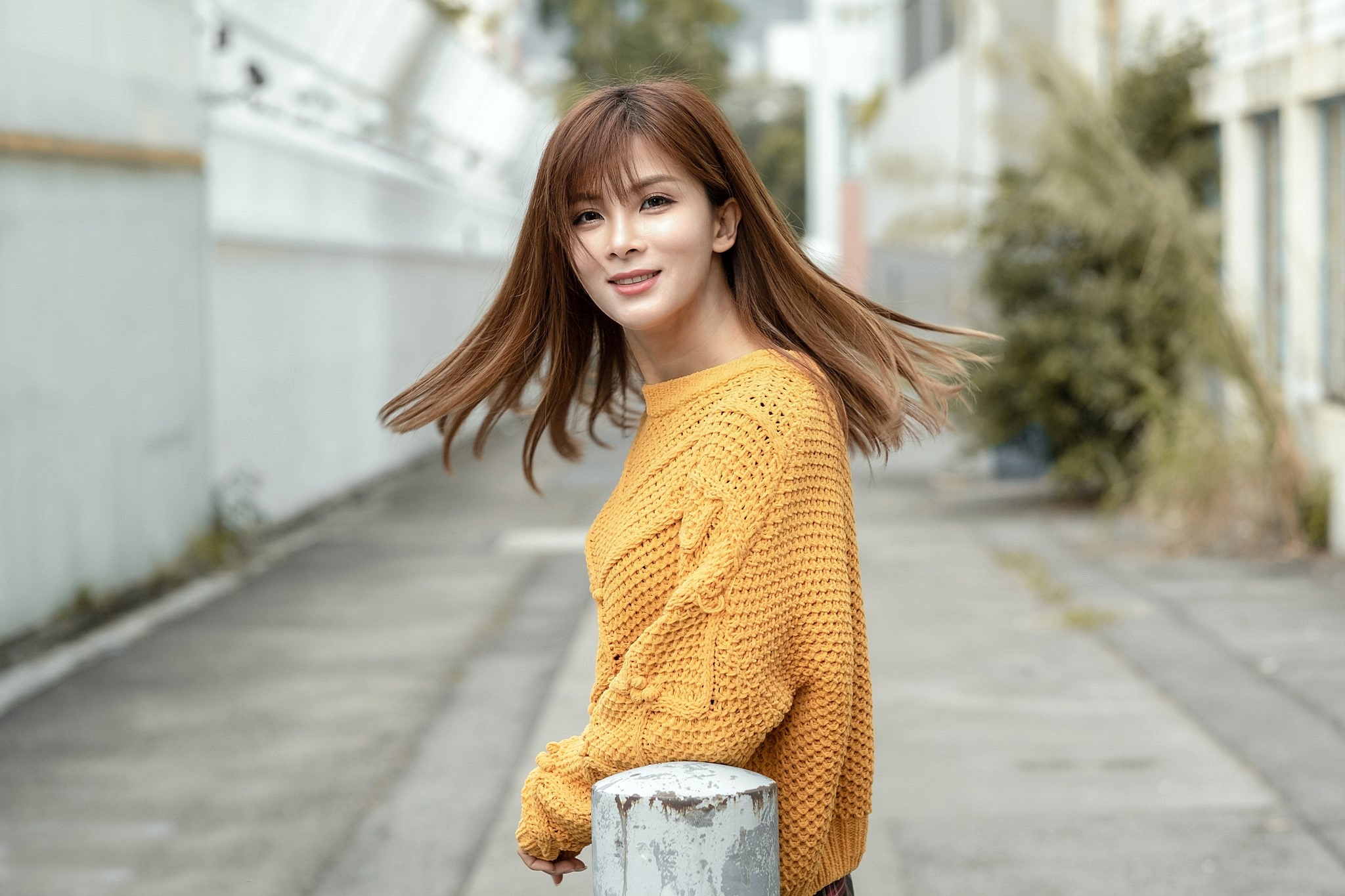 Young Woman in Yellow Sweater Smiling Outdoors HD Wallpaper