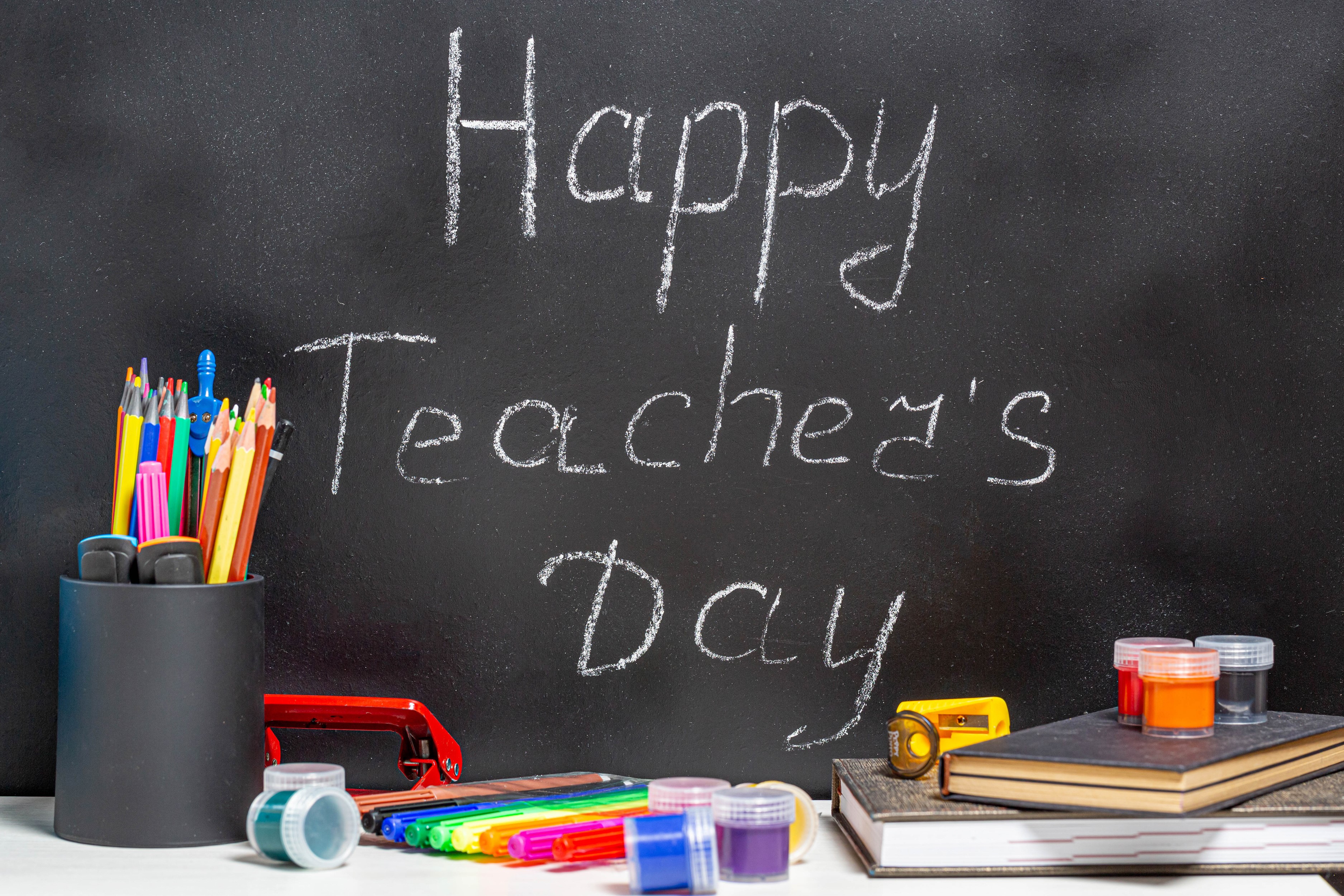Happy Teacher's Day chalk message on blackboard with school supplies HD Wallpaper