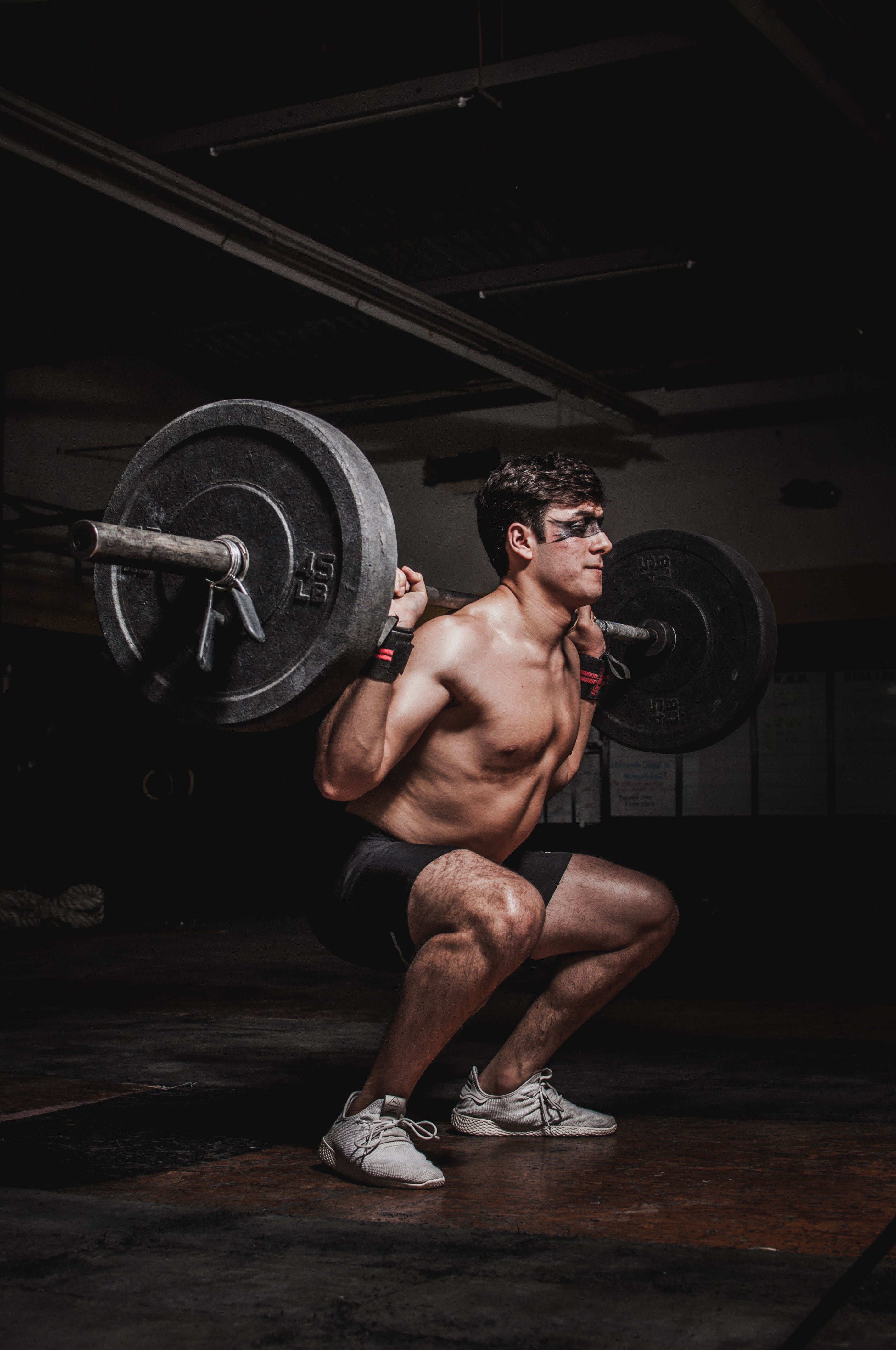 Man performing barbell squats in a gym HD Phone Wallpaper