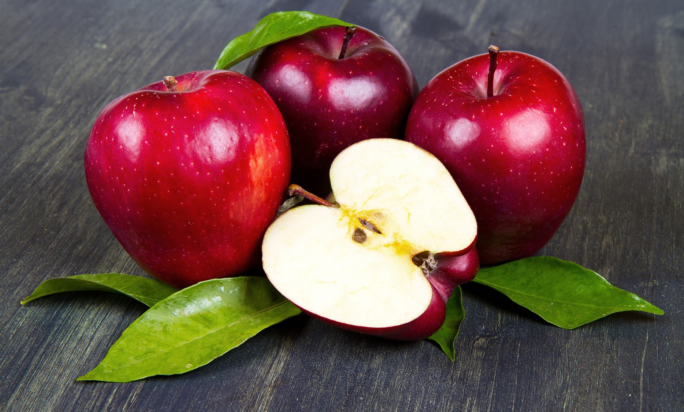 Red apples with leaves on a dark wooden surface HD Wallpaper