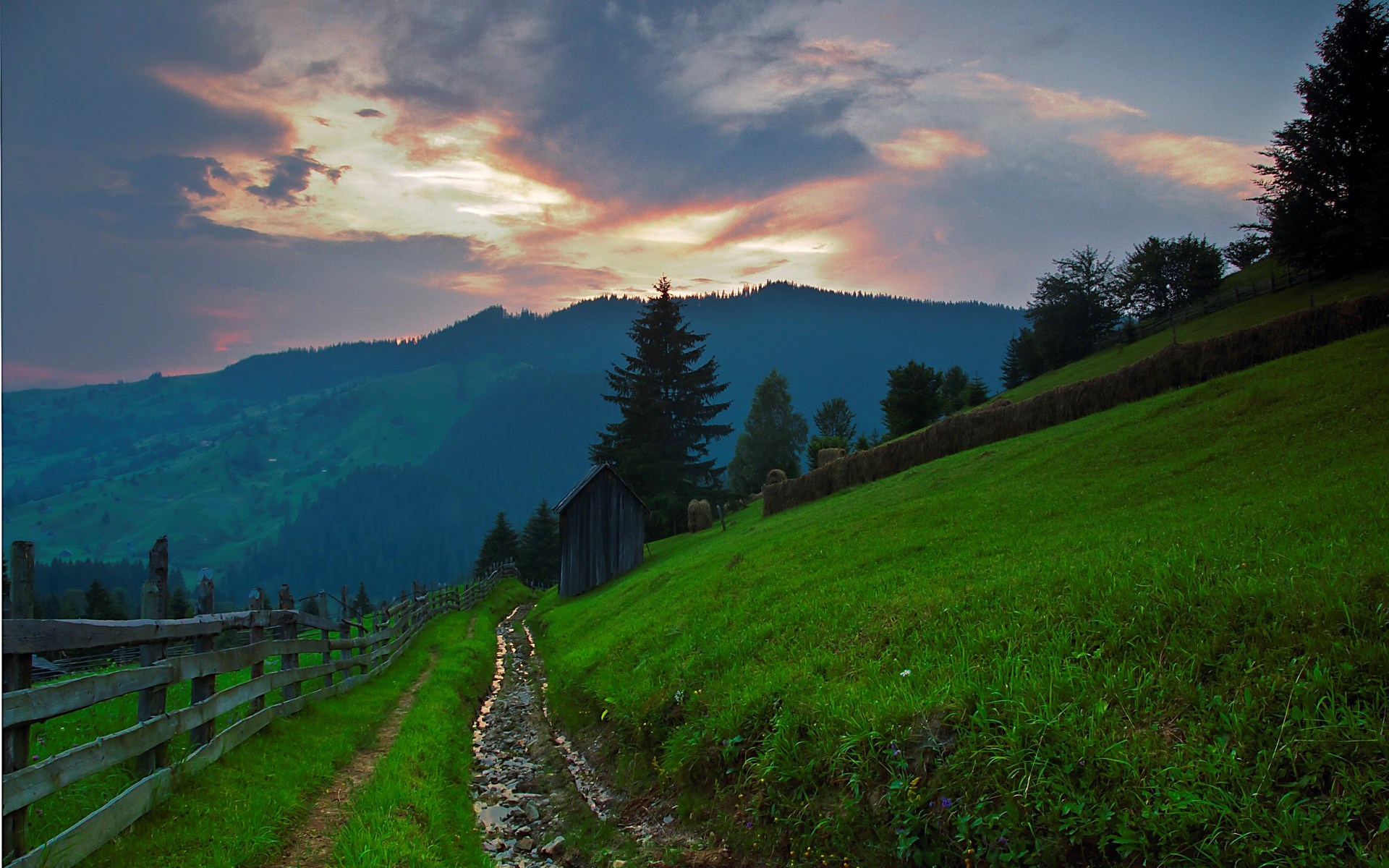Mountain landscape with a wooden fence and a stream at sunset HD Wallpaper