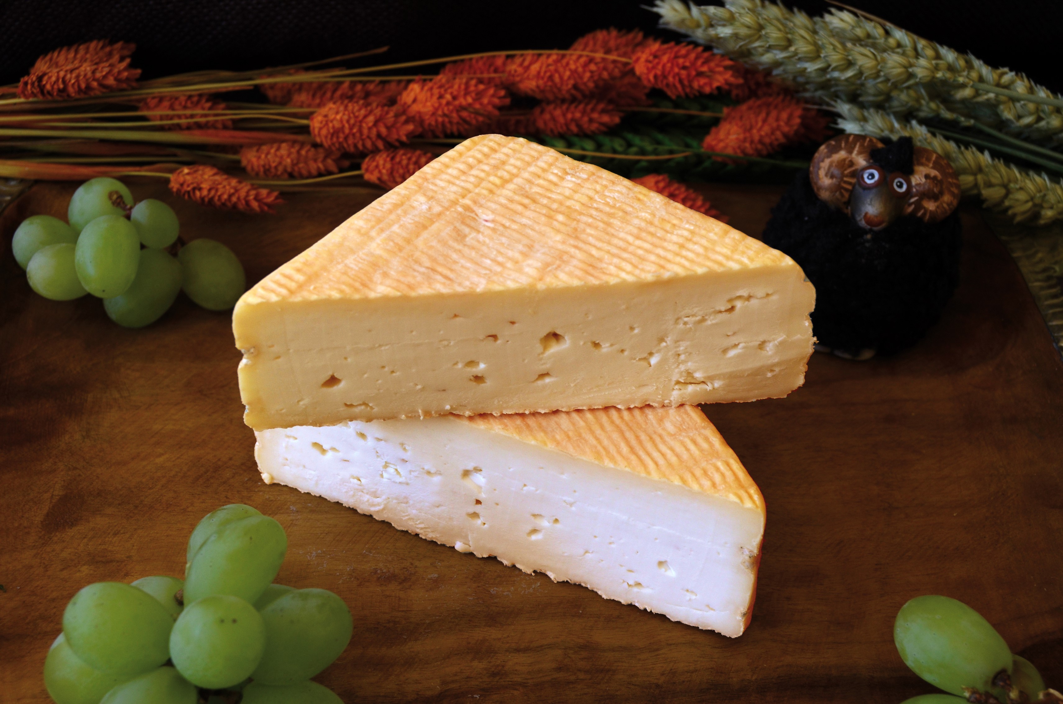 Wedge of cheese with grapes and a sheep figurine HD Wallpaper