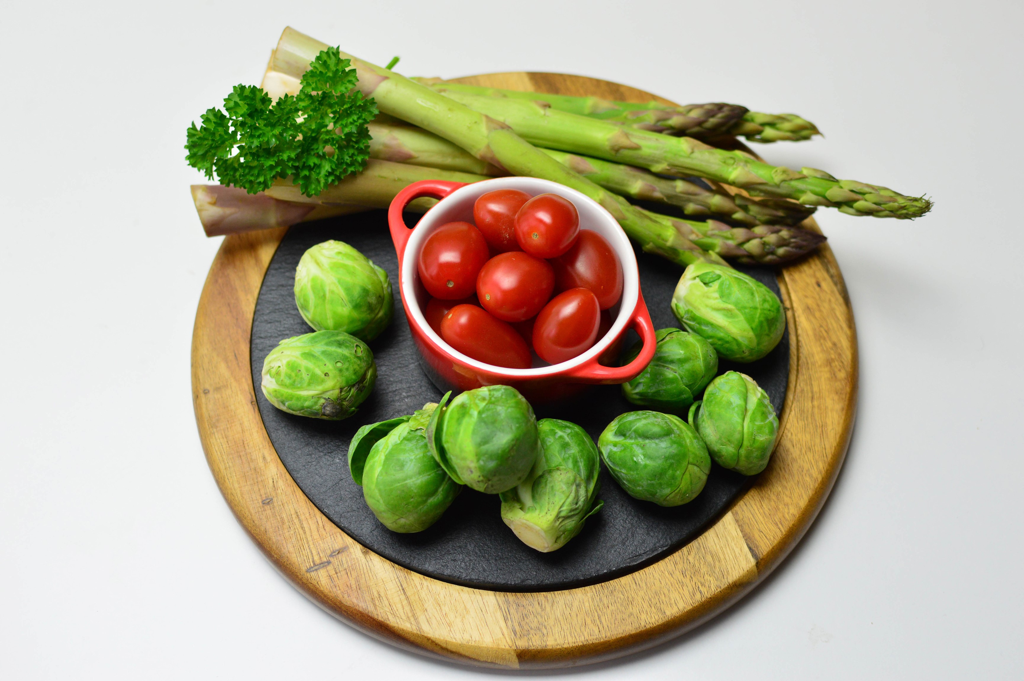 Asparagus, Brussels sprouts, and tomatoes on a cutting board HD Wallpaper
