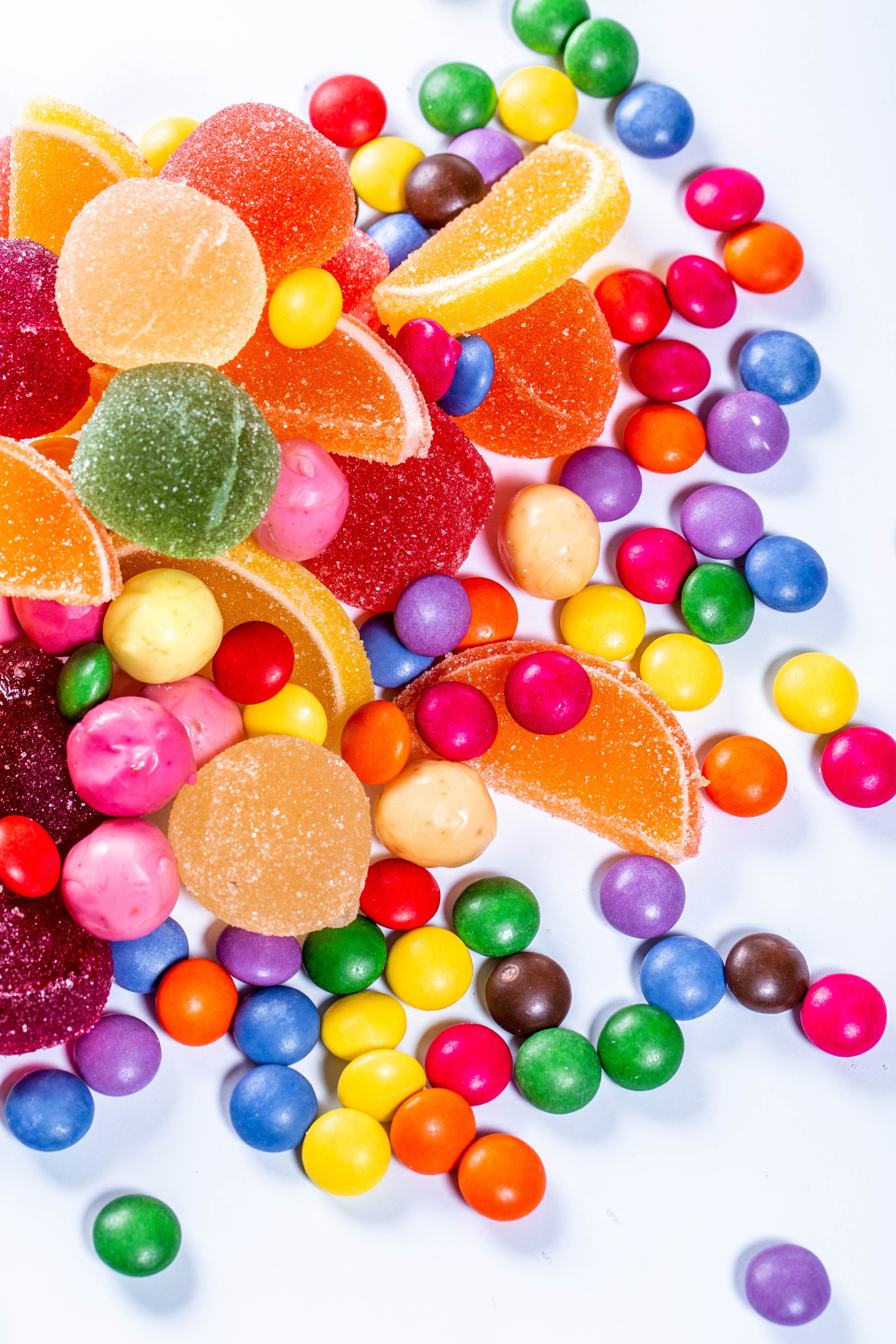 Assortment of colorful candies and marmalades on a white background HD Phone Wallpaper