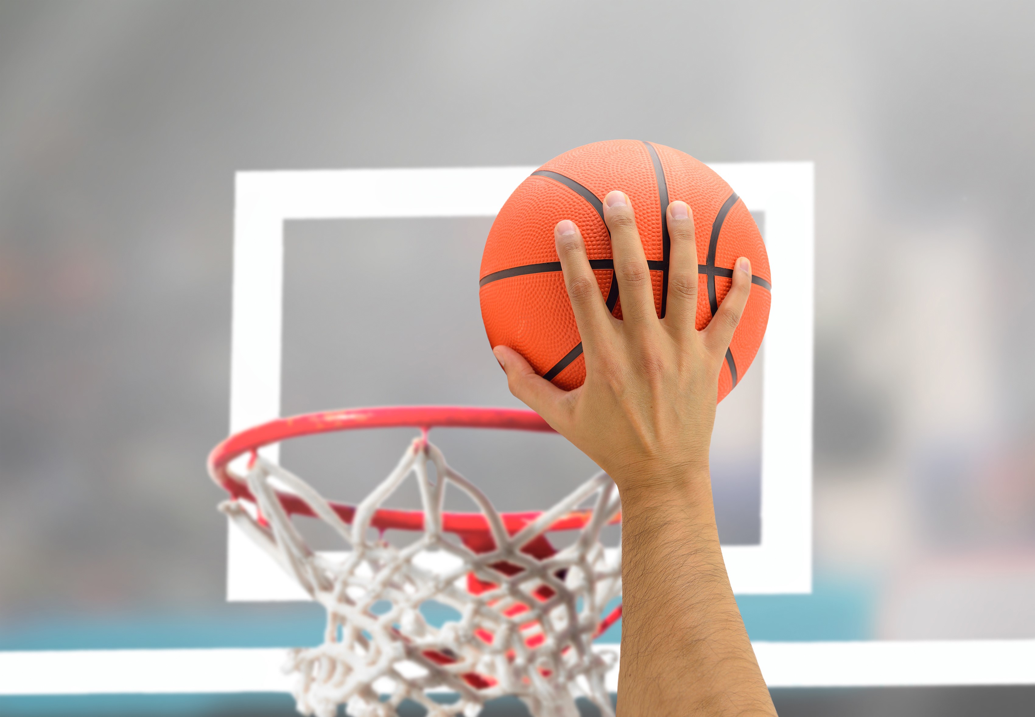 Hand holding a basketball near a hoop HD Wallpaper
