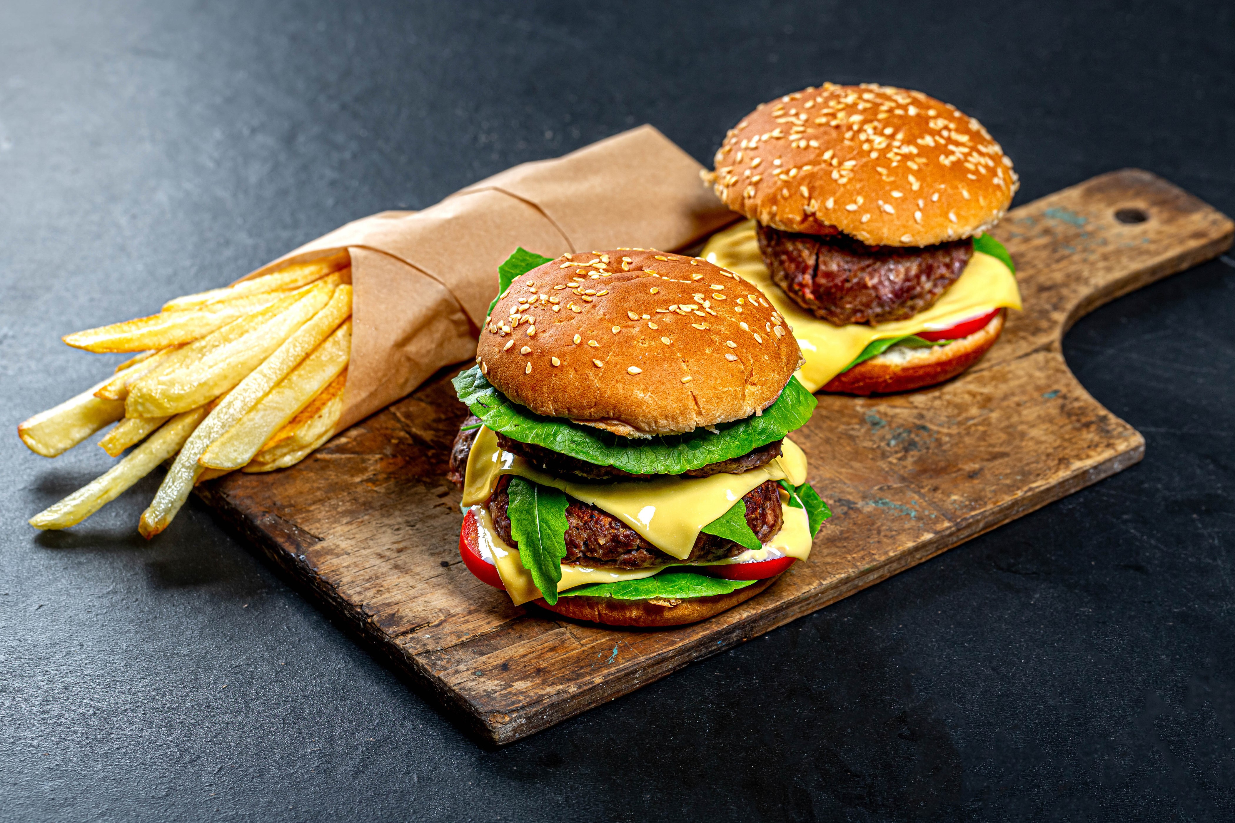 Two hamburgers and french fries on a cutting board HD Wallpaper