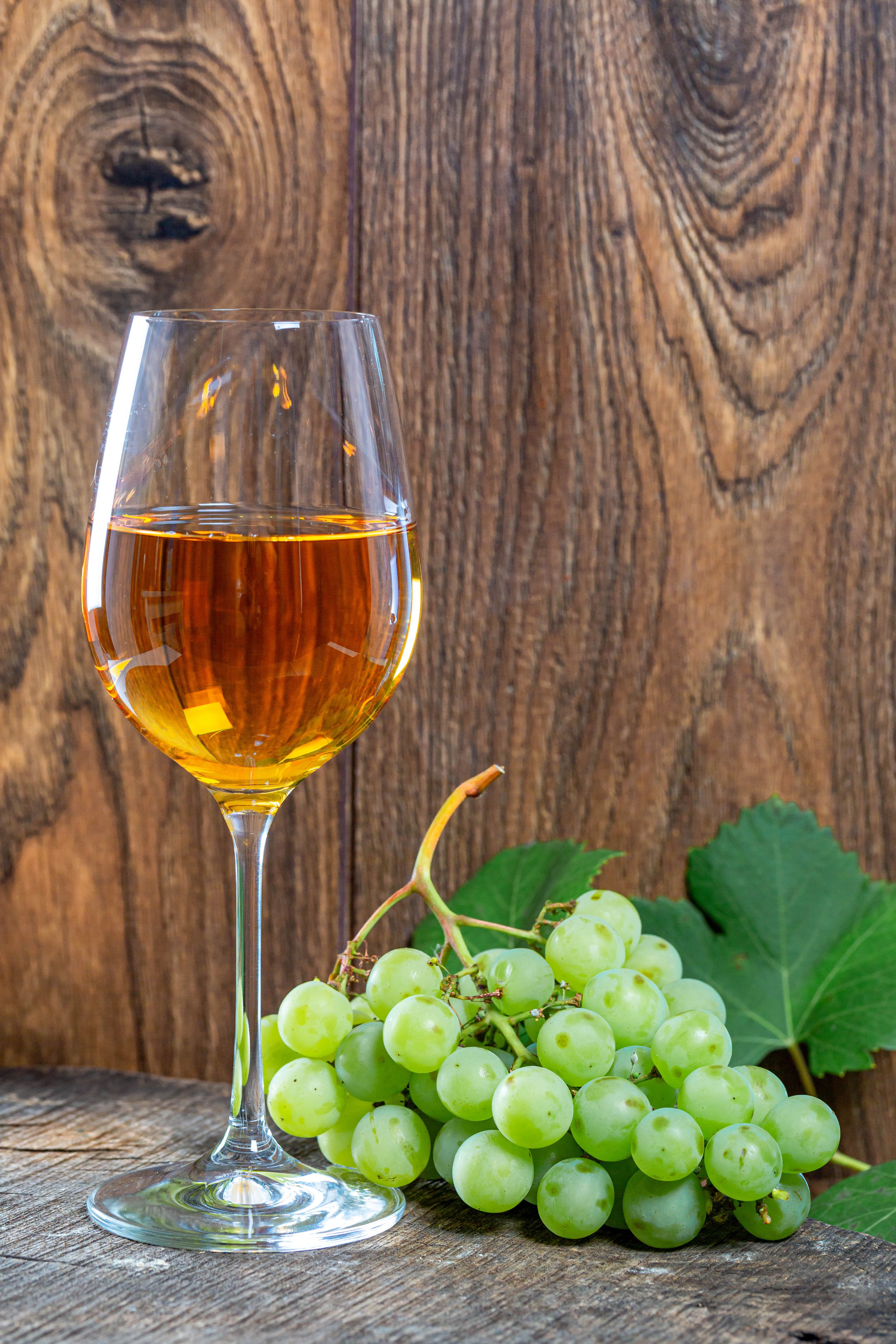 Glass of amber wine with green grapes on wood HD Phone Wallpaper