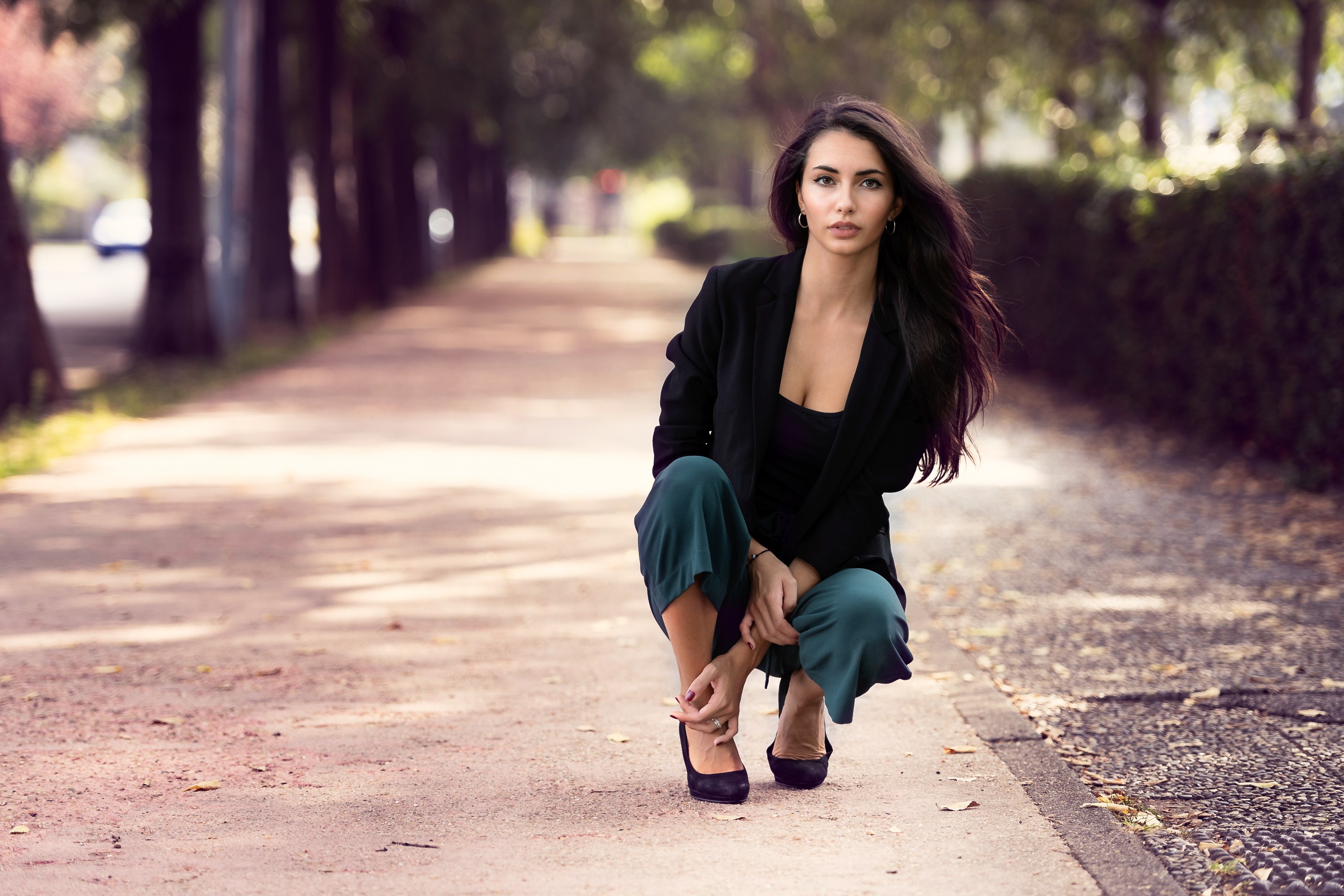 Woman in black blazer and green pants posing outdoors HD Wallpaper