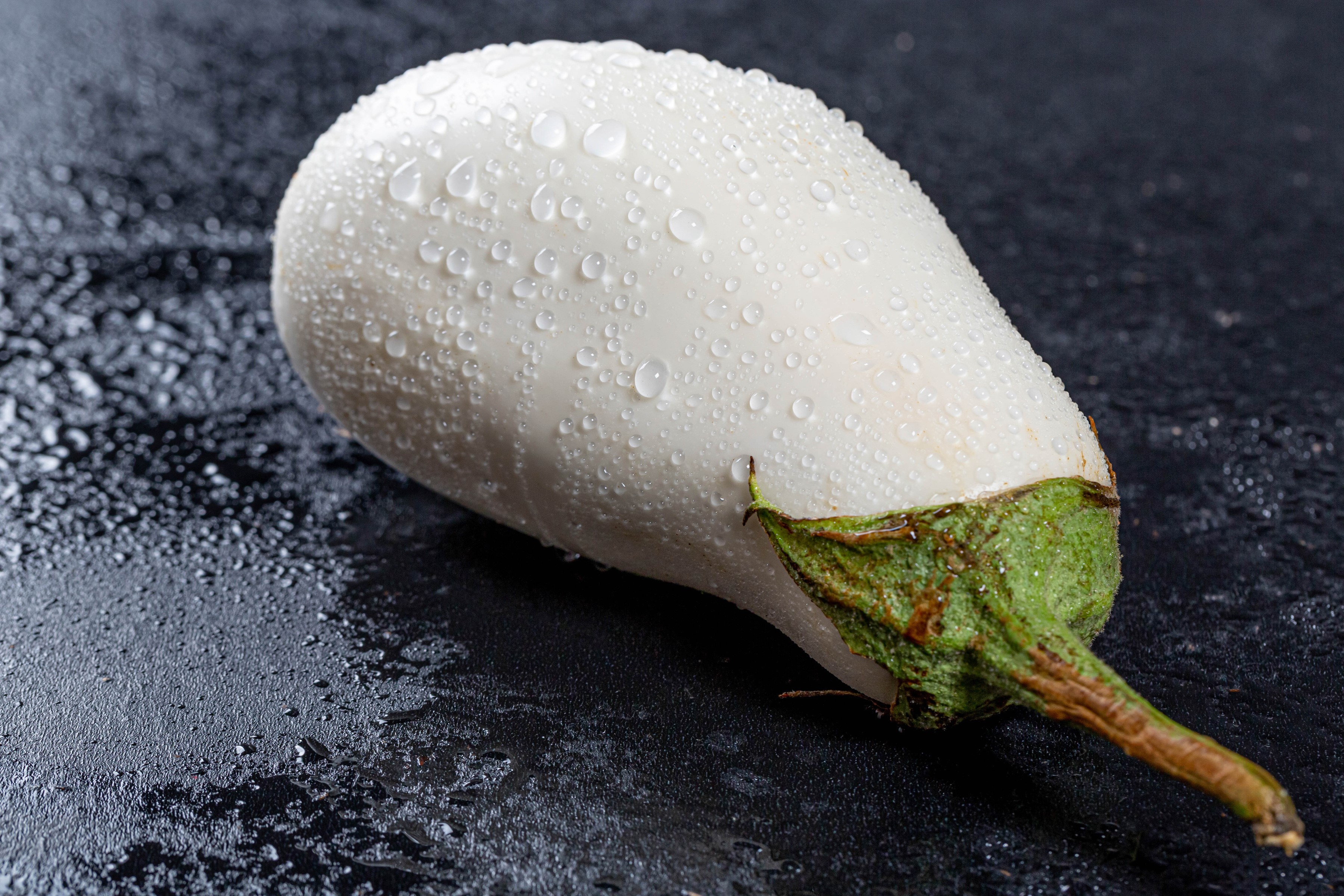 White eggplant with water drops on dark surface HD Wallpaper