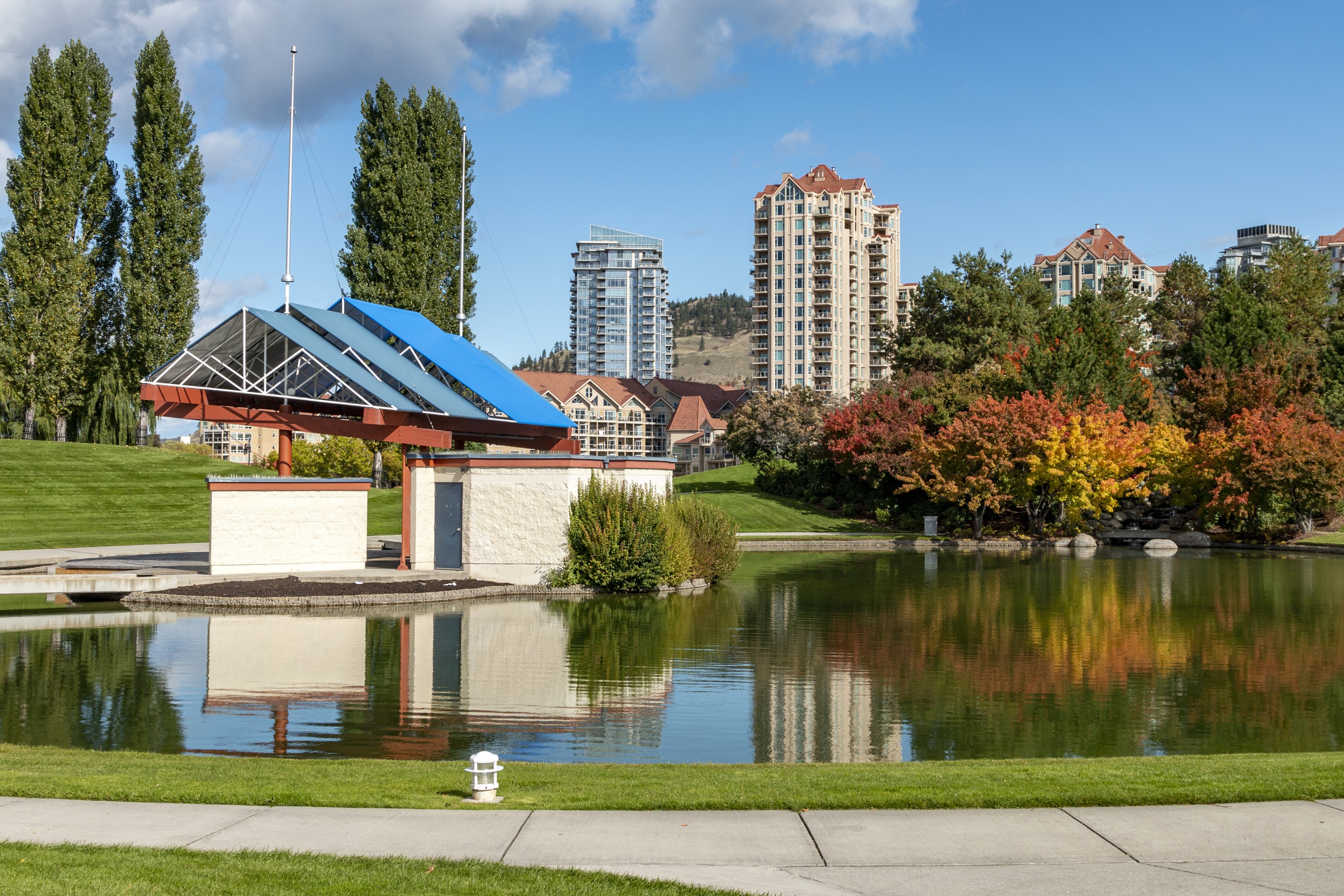 Park with pond and buildings in Kelowna, Canada during autumn HD Wallpaper