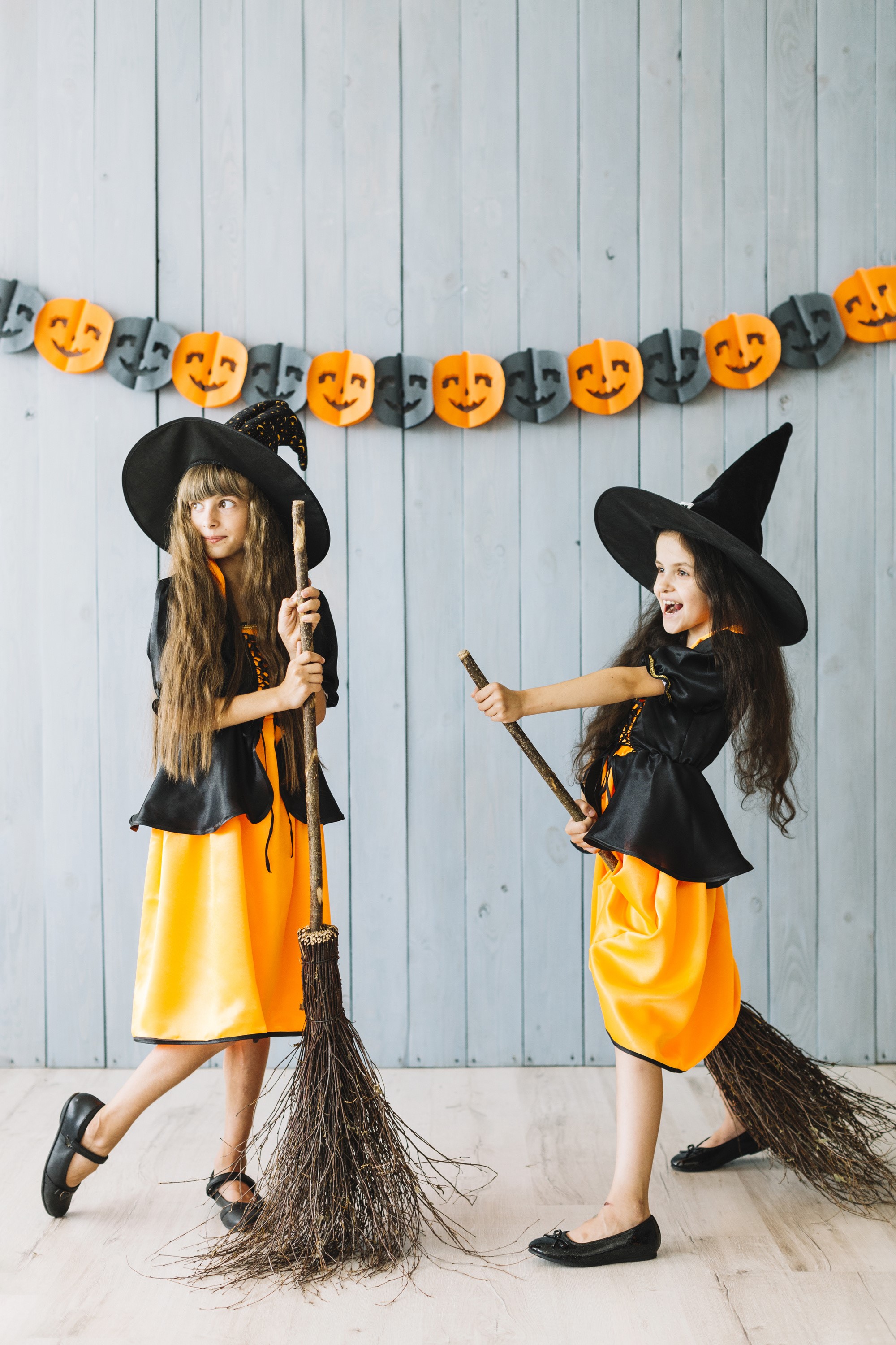 Two young girls dressed as witches holding brooms HD Phone Wallpaper