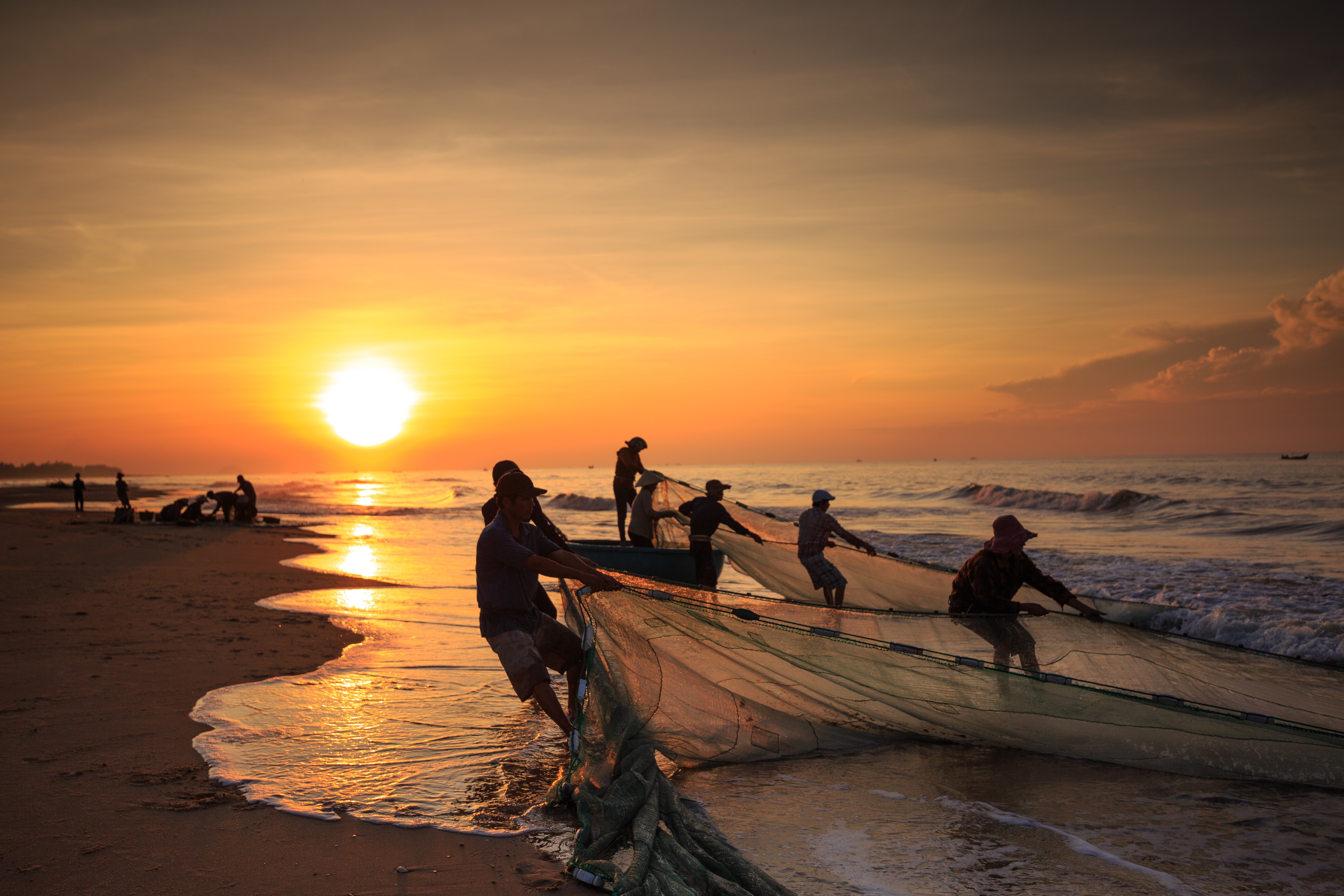Fishermen pulling nets at sunrise on Asian coast HD Wallpaper