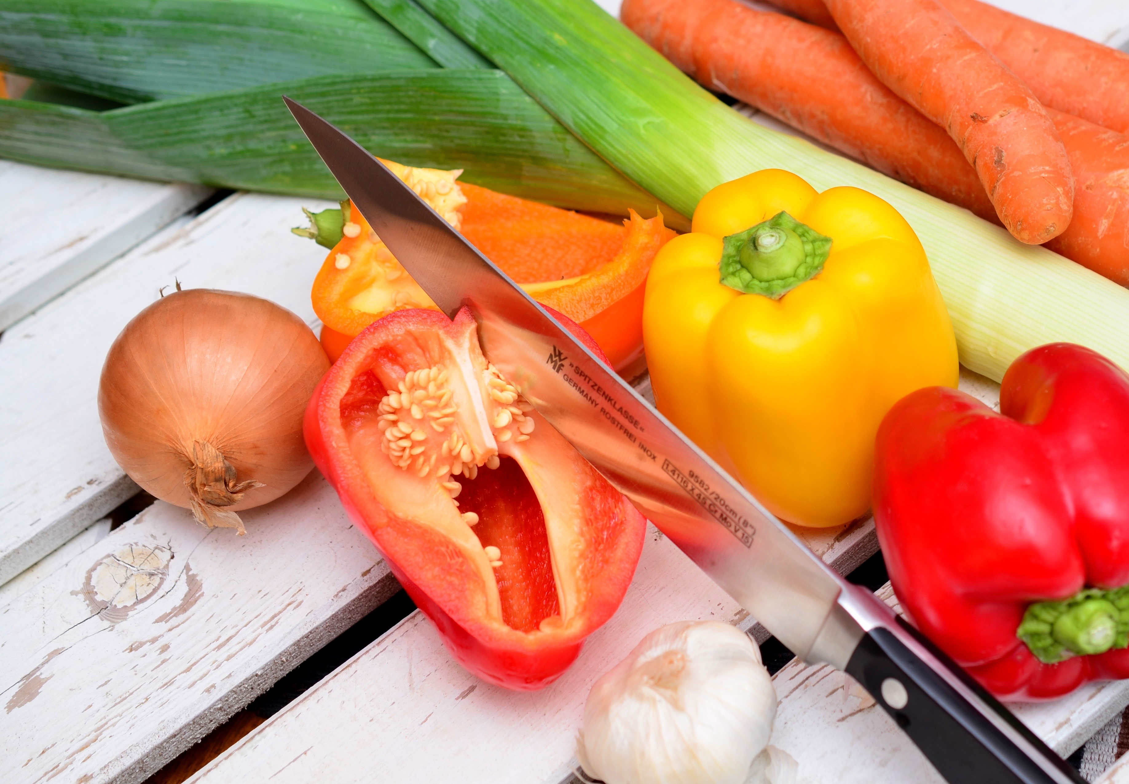 Knife cutting bell pepper with vegetables HD Wallpaper