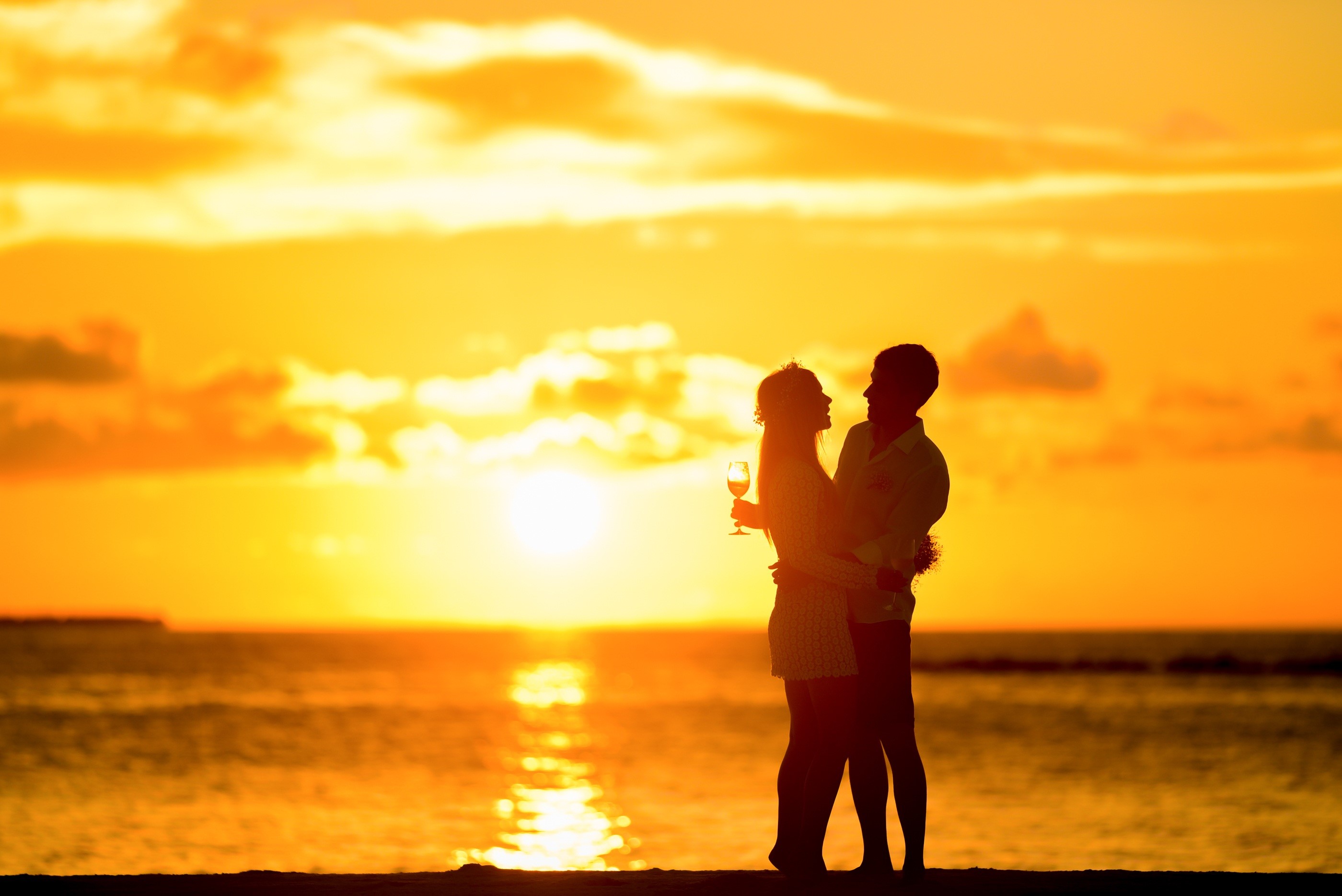 Couple hugging at sunset on a beach HD Wallpaper