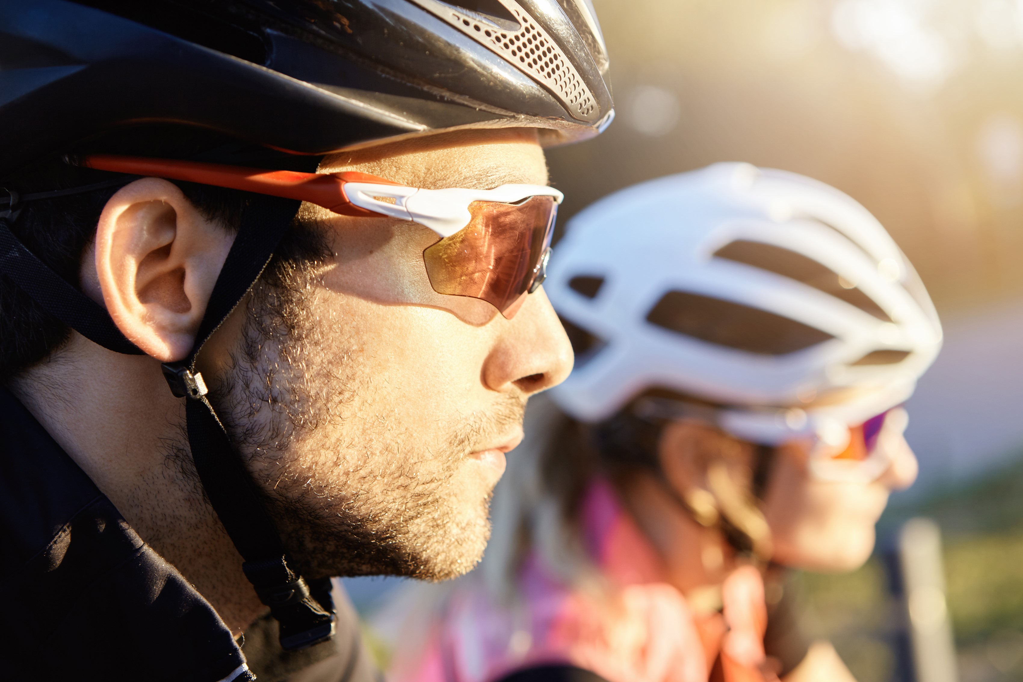 Two cyclists wearing helmets and sunglasses HD Wallpaper