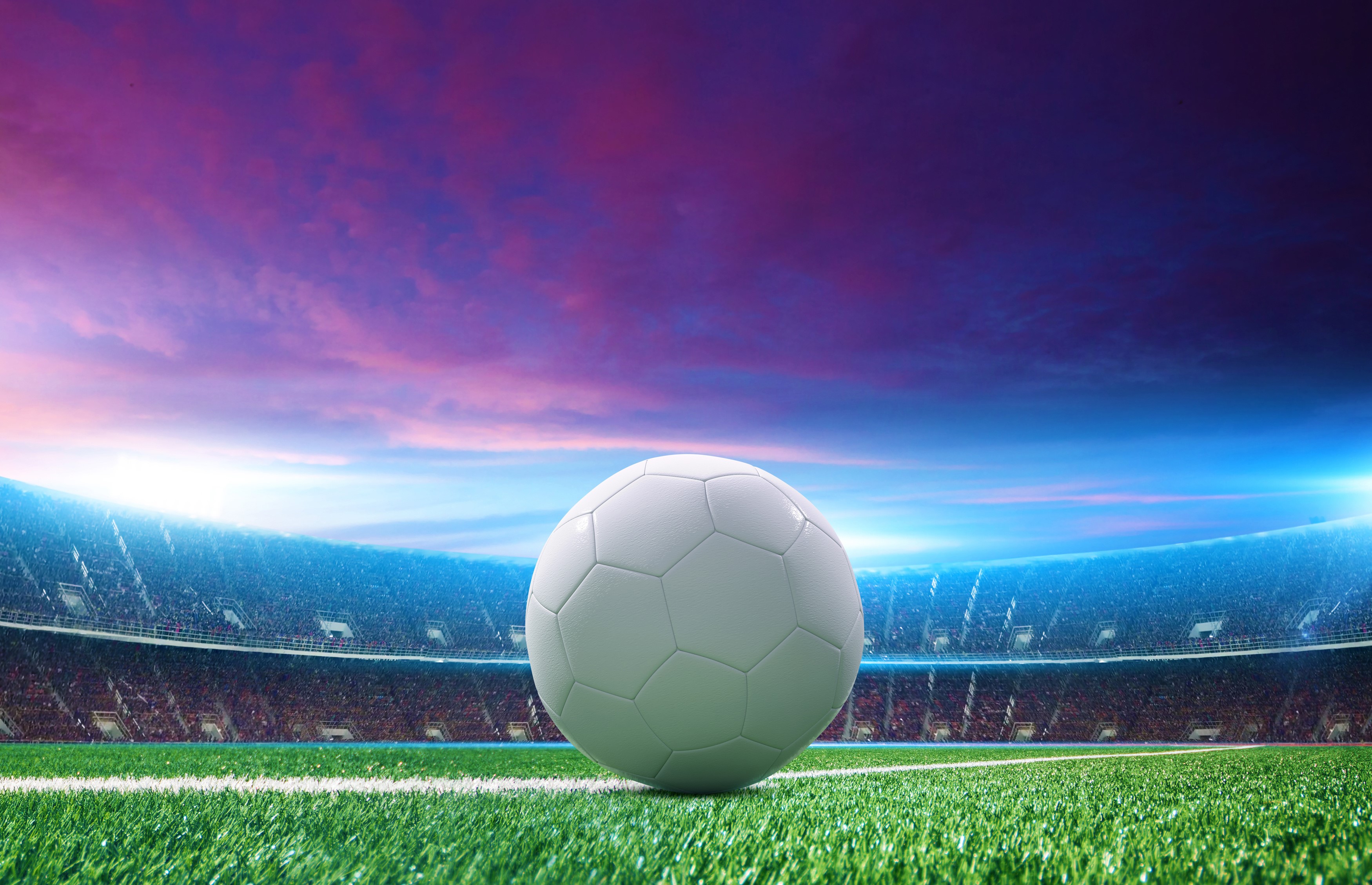 Soccer ball on a stadium field at sunset HD Wallpaper