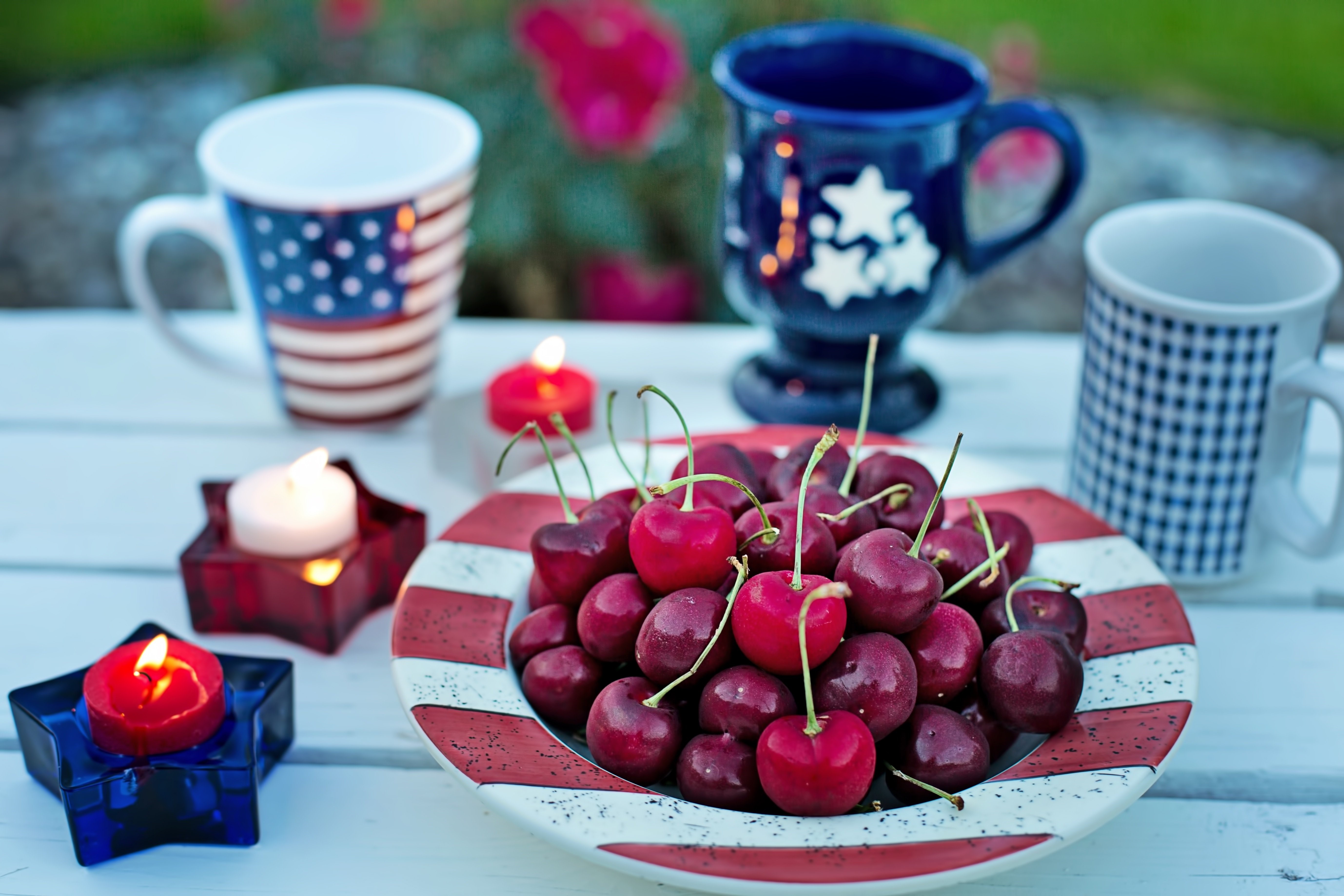 Cherries on a plate with American-themed mugs and candles HD Wallpaper