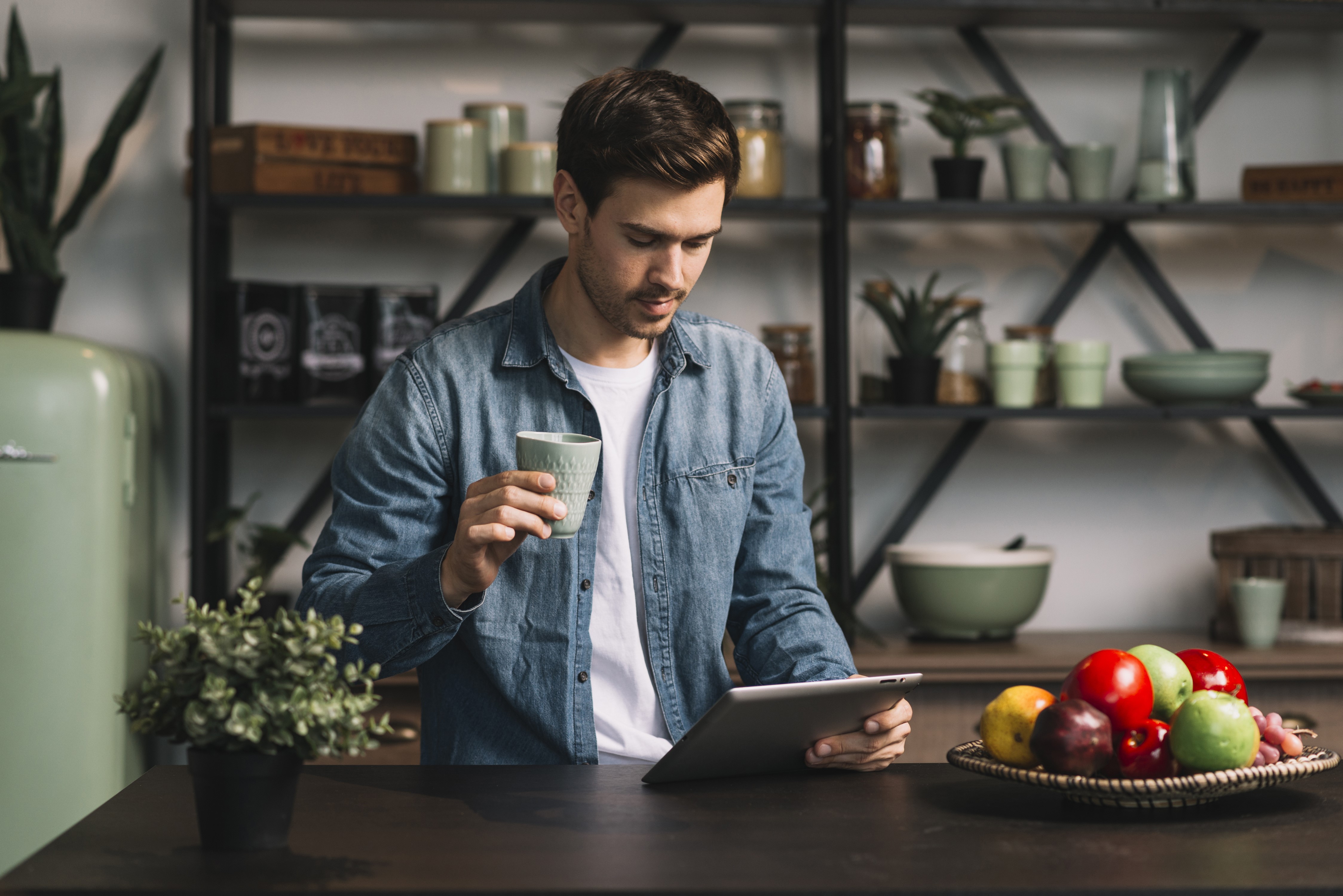 Man holding cup and tablet in kitchen HD Wallpaper