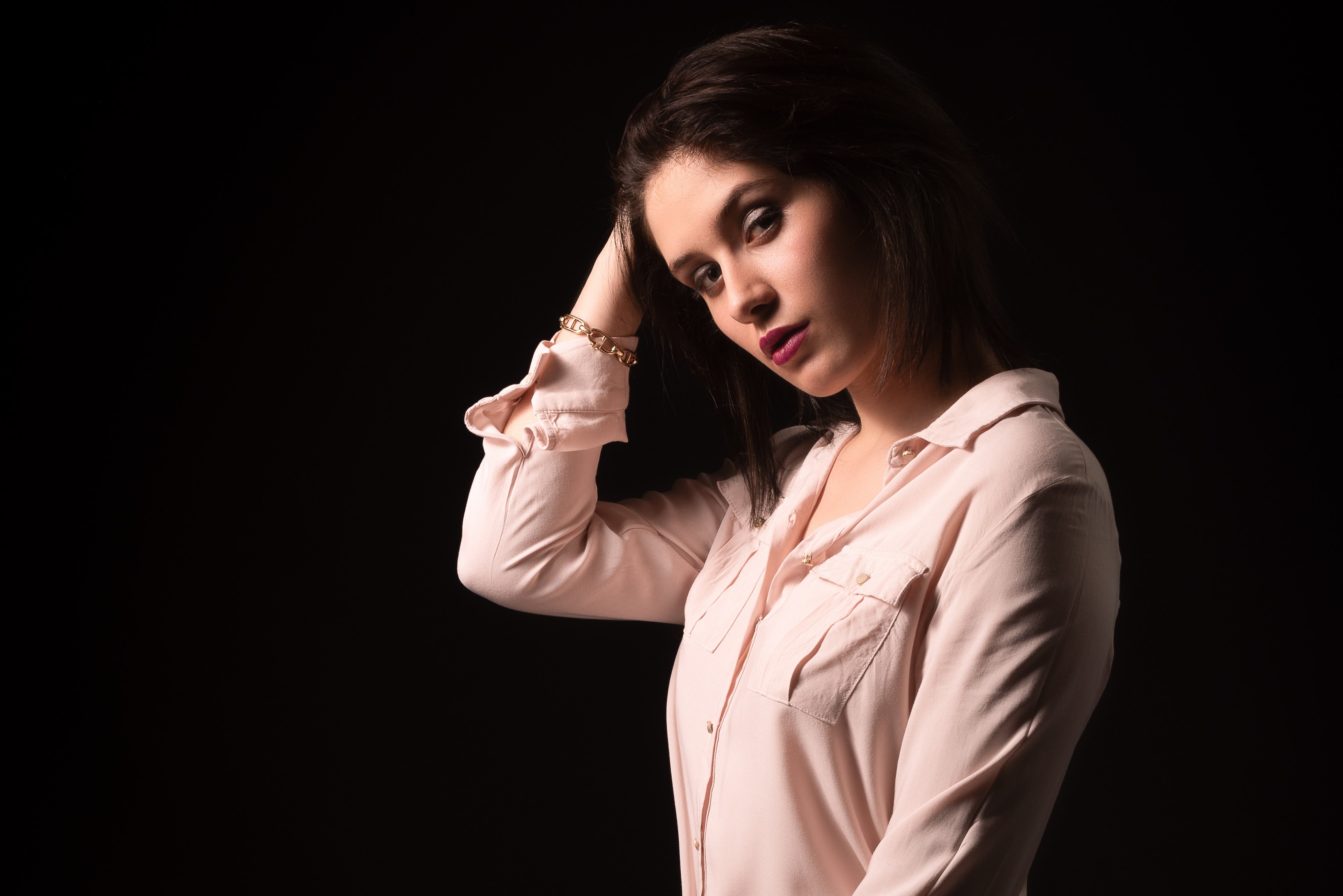 Woman in a pink shirt posing against a black background HD Wallpaper