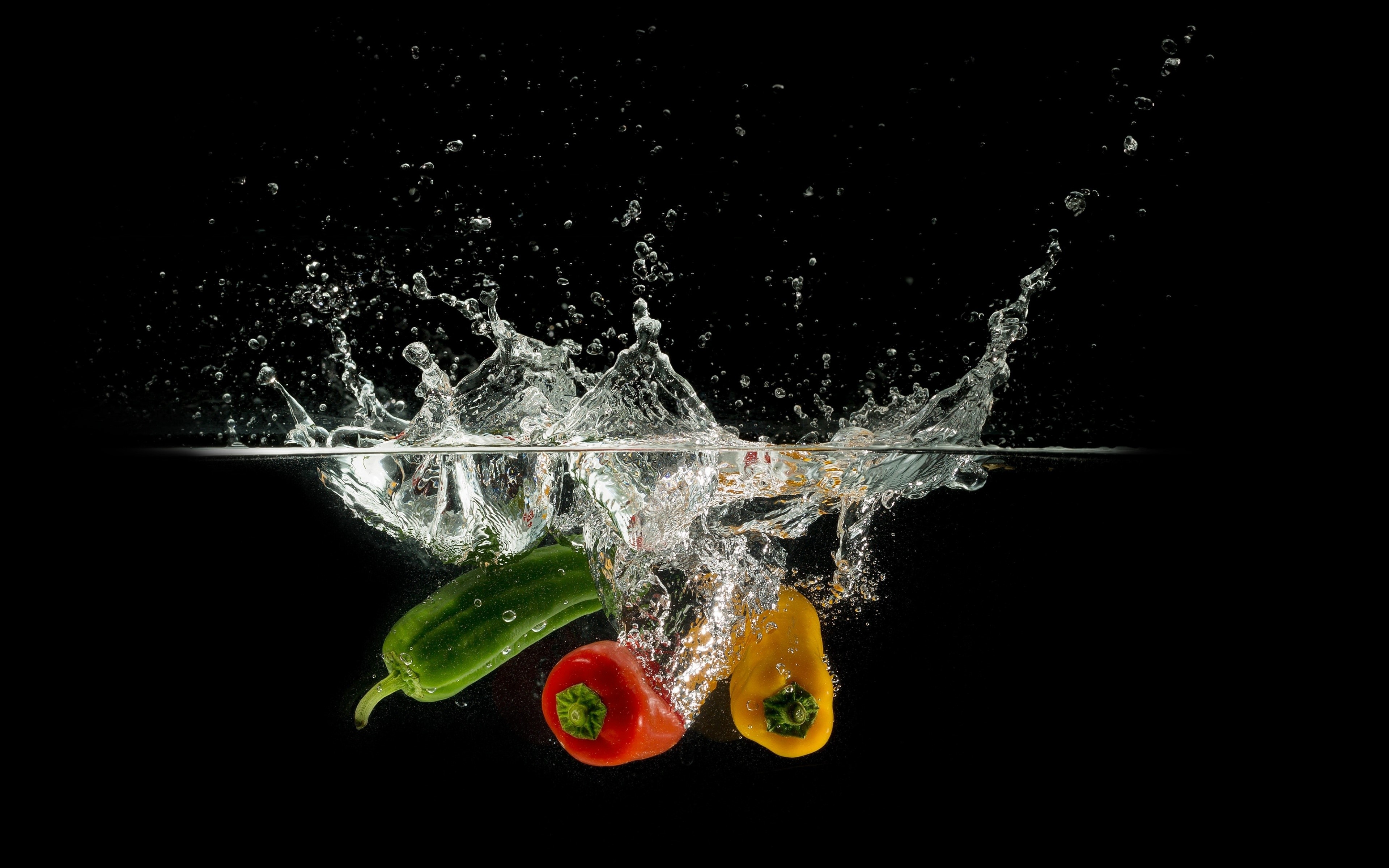 Bell peppers splashing into water on black background HD Wallpaper