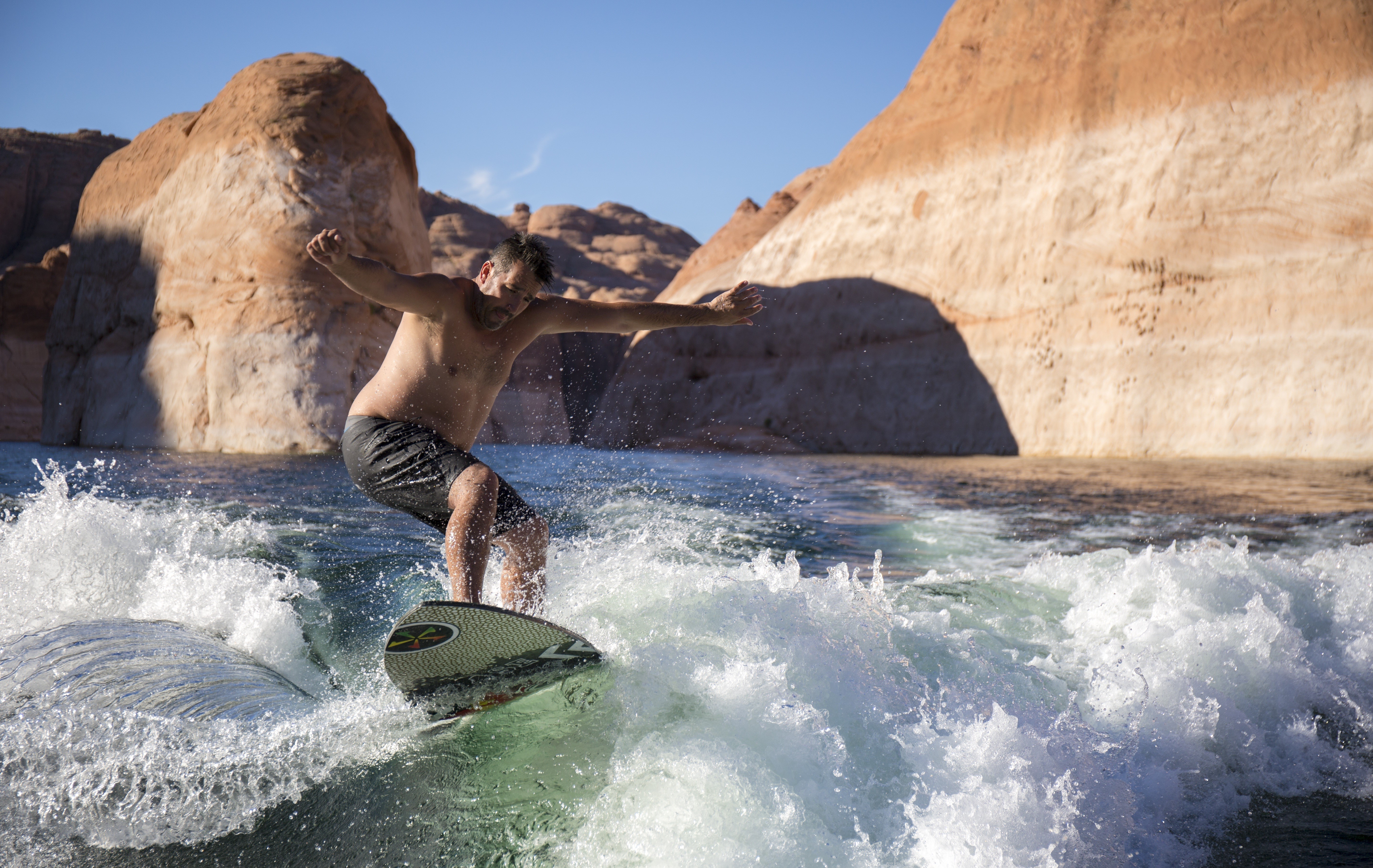 Man wakesurfing in front of sandstone cliffs HD Wallpaper