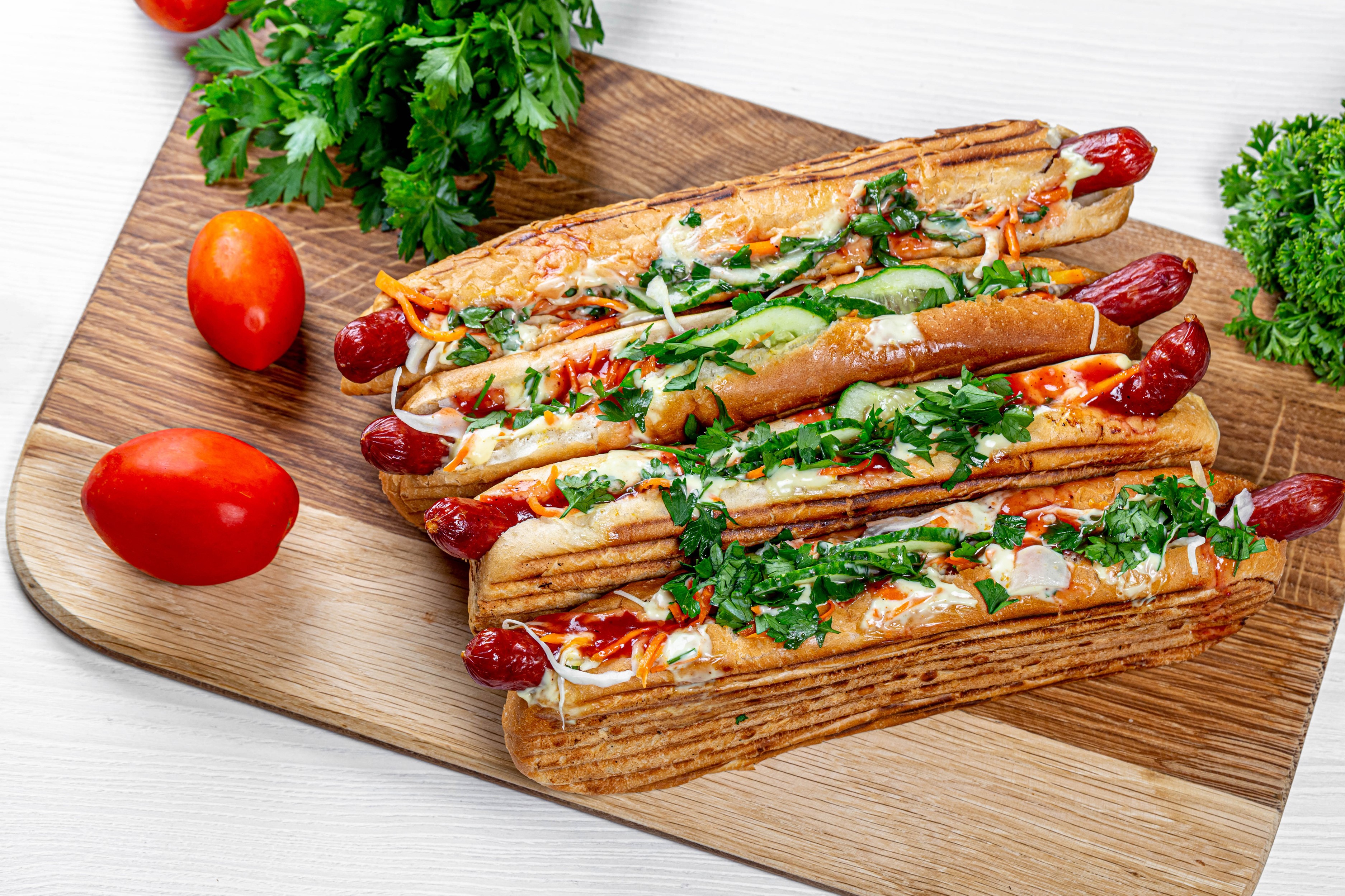 Four hot dogs with toppings on a cutting board HD Wallpaper