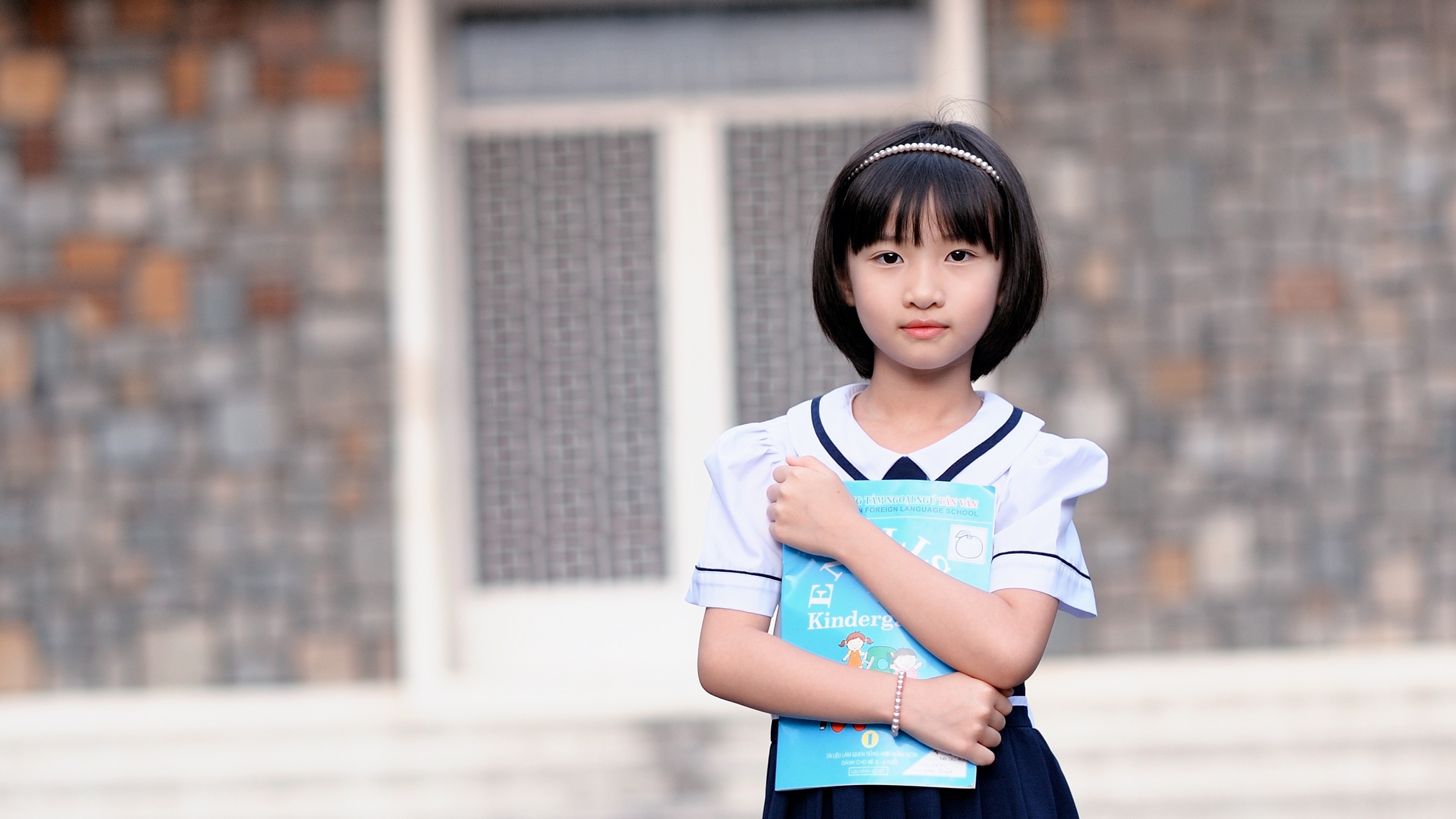 Young Schoolgirl Holding a Blue Book Outdoors HD Wallpaper