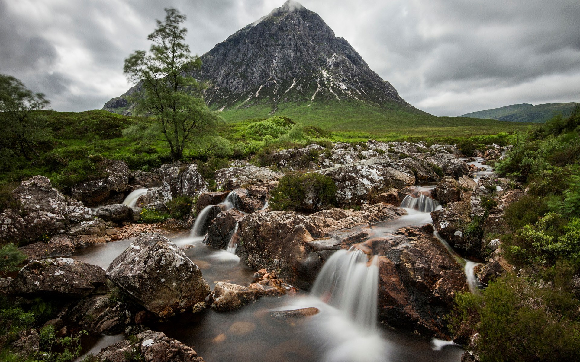 Mountain stream flowing over rocks with a large mountain in the background HD Wallpaper