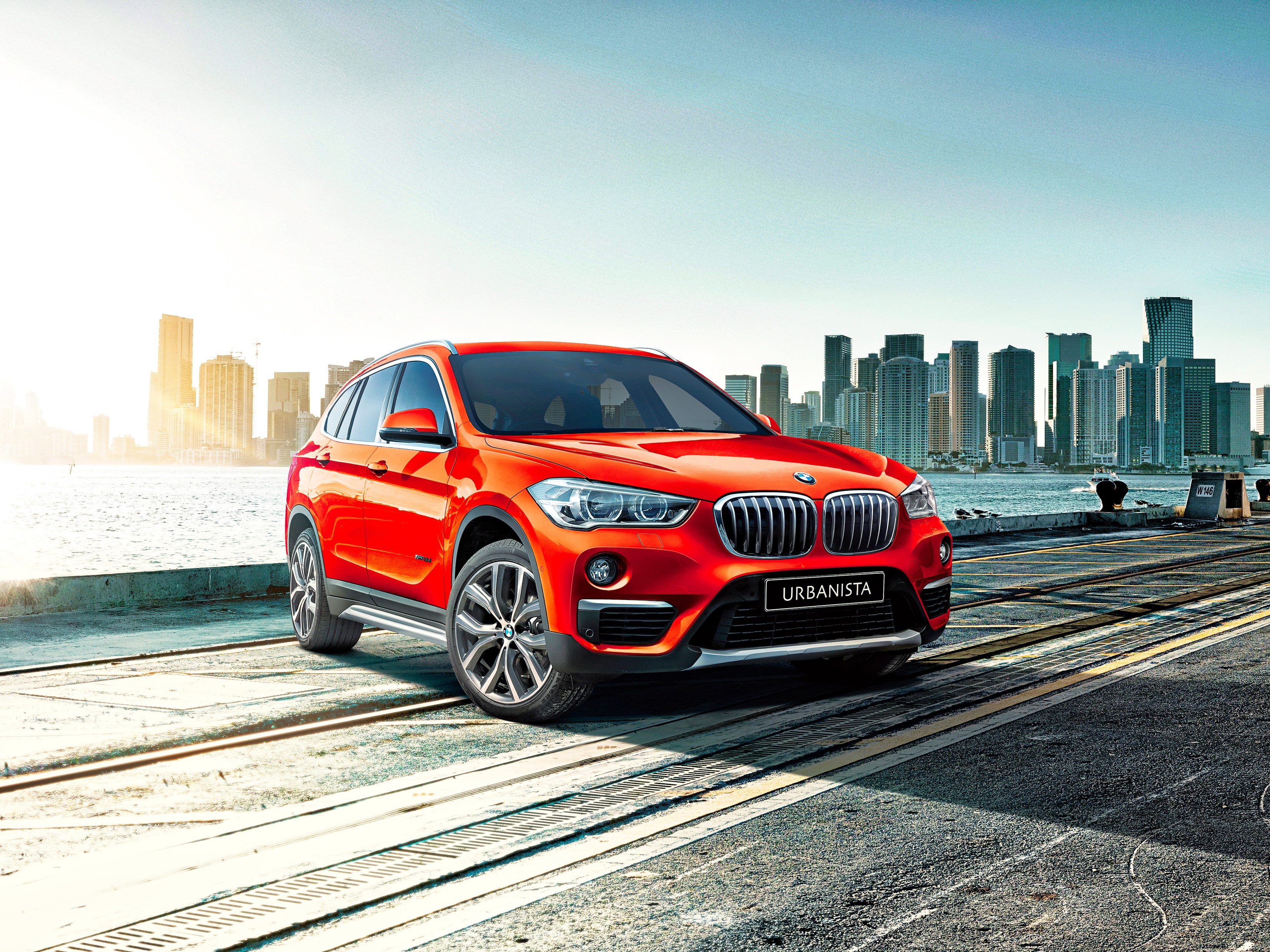Red BMW X1 Urbanista parked by a city skyline HD Wallpaper
