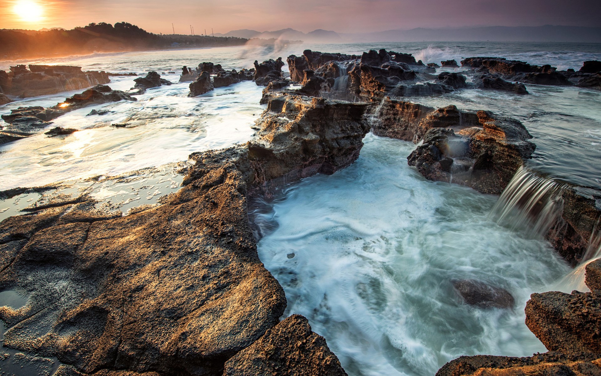 Rocky coastline with waves crashing at sunset HD Wallpaper