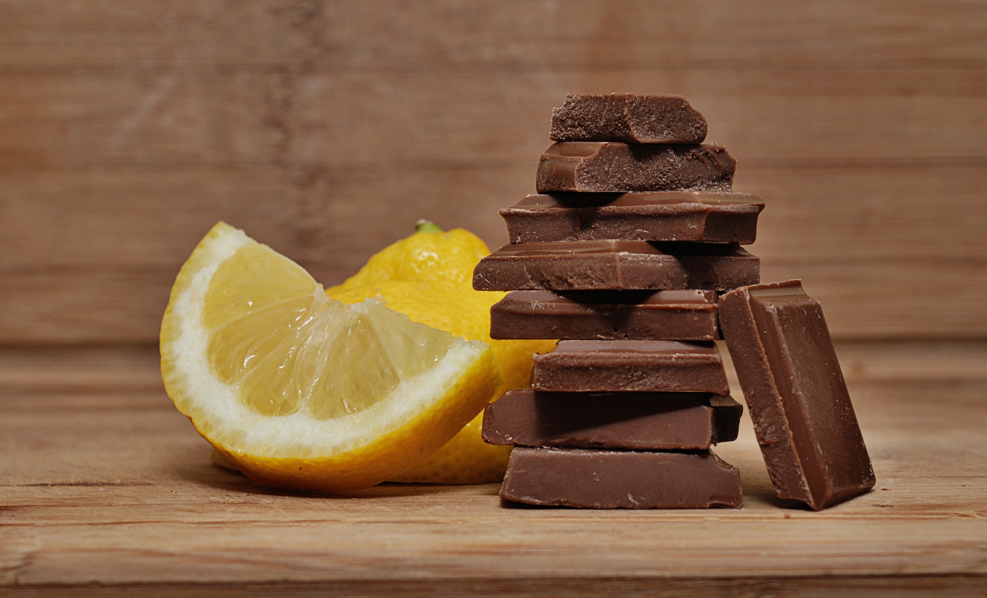 Chocolate pieces and lemons on a wooden surface HD Wallpaper