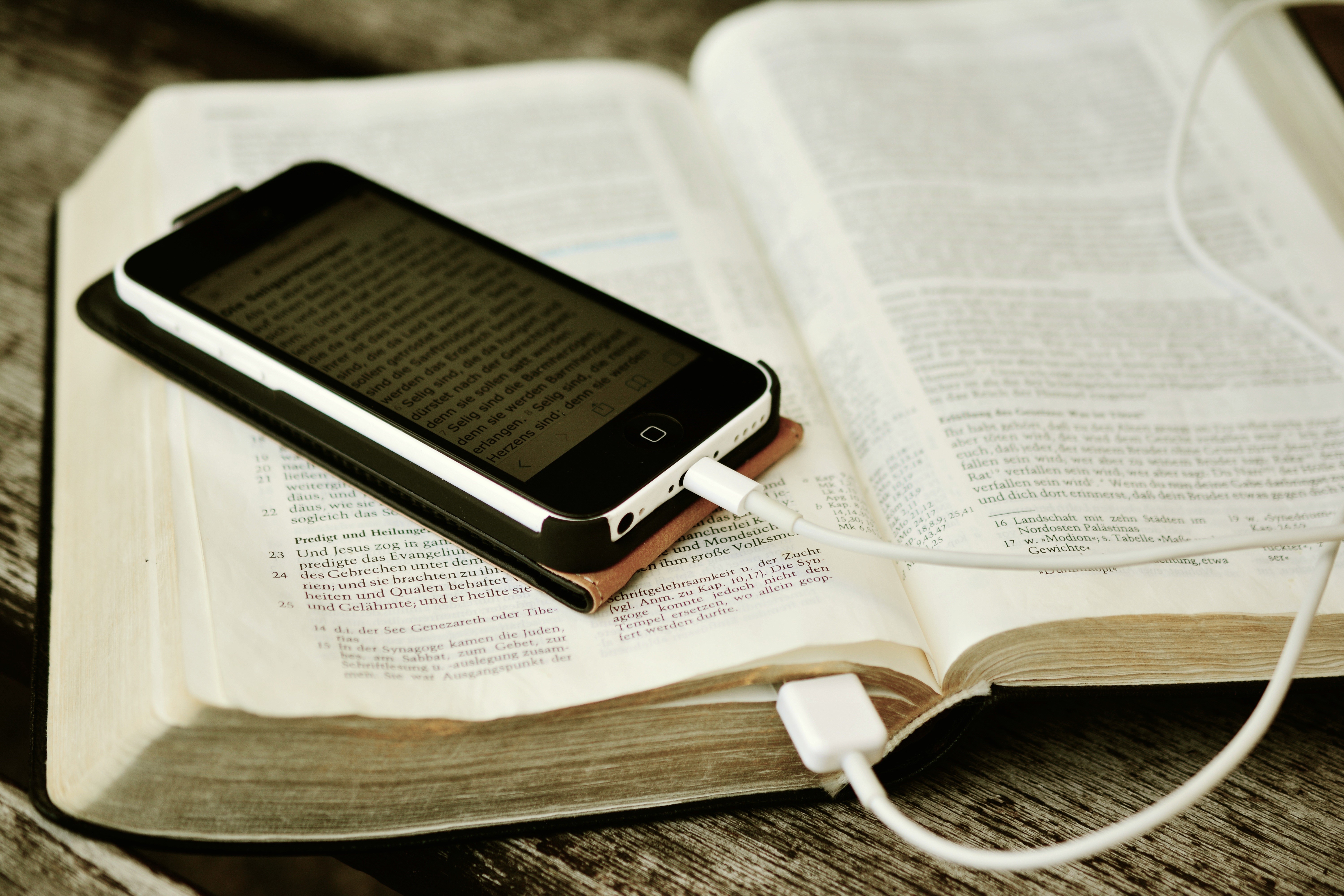 Smartphone charging on an open Bible HD Wallpaper