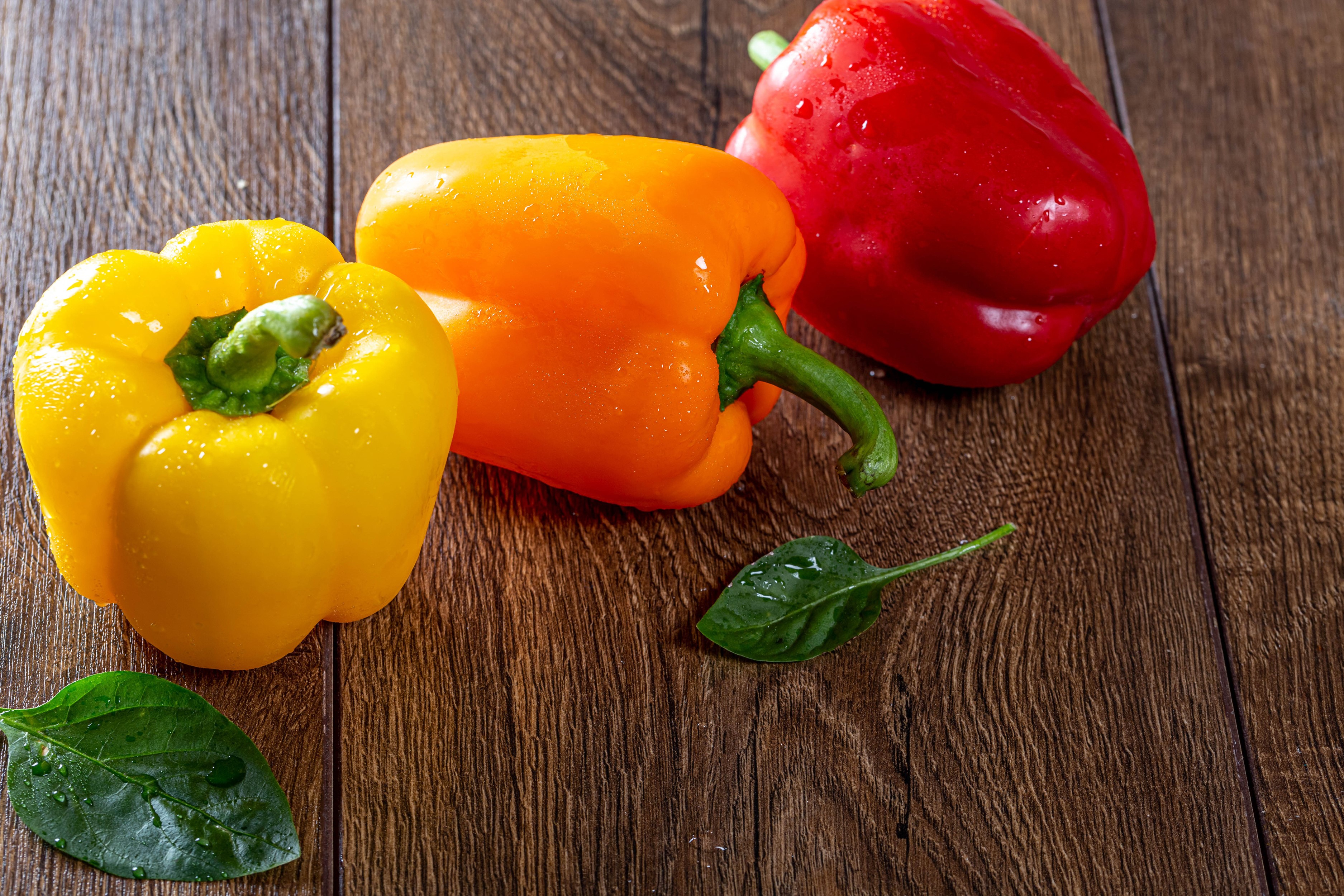 Three bell peppers on a wooden surface HD Wallpaper