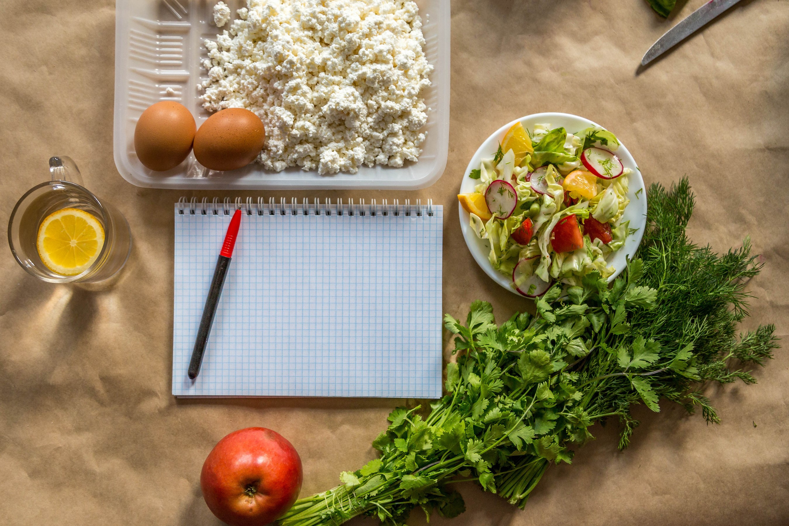 Cottage cheese, eggs, salad, apple, and notepad on a table HD Wallpaper