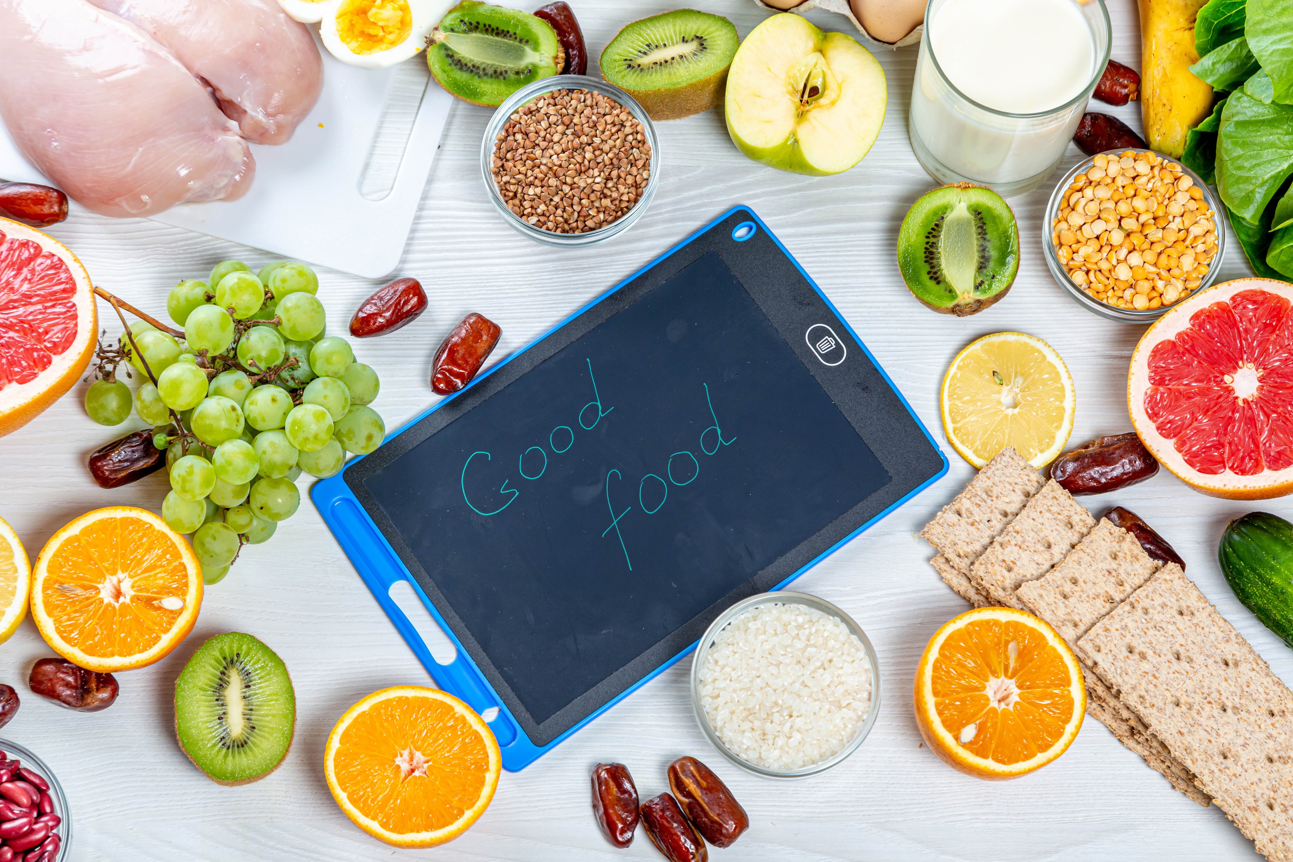 Good food written on a digital tablet surrounded by fruits and grains HD Wallpaper
