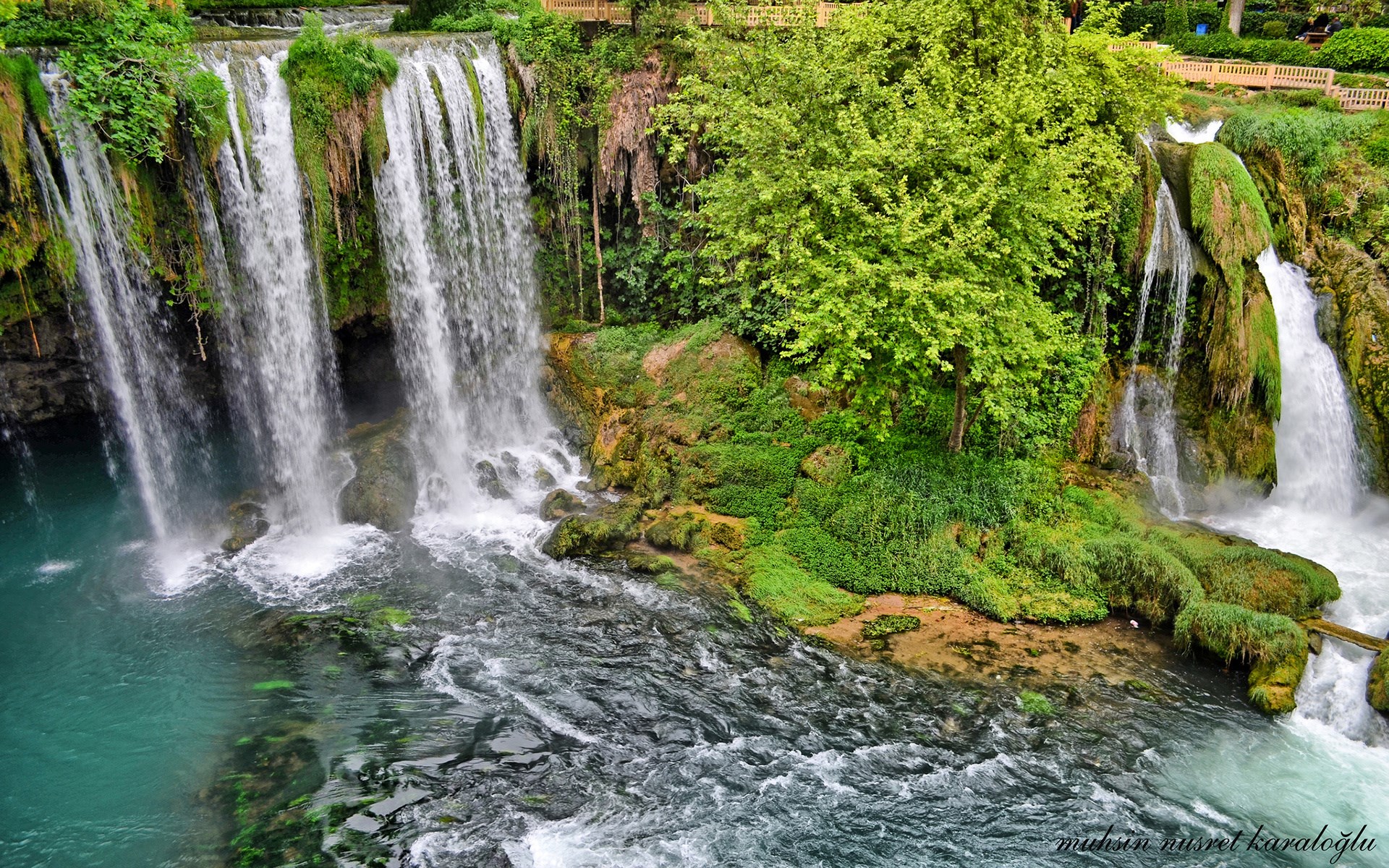 Waterfalls cascading over mossy rocks into a turquoise pool HD Wallpaper