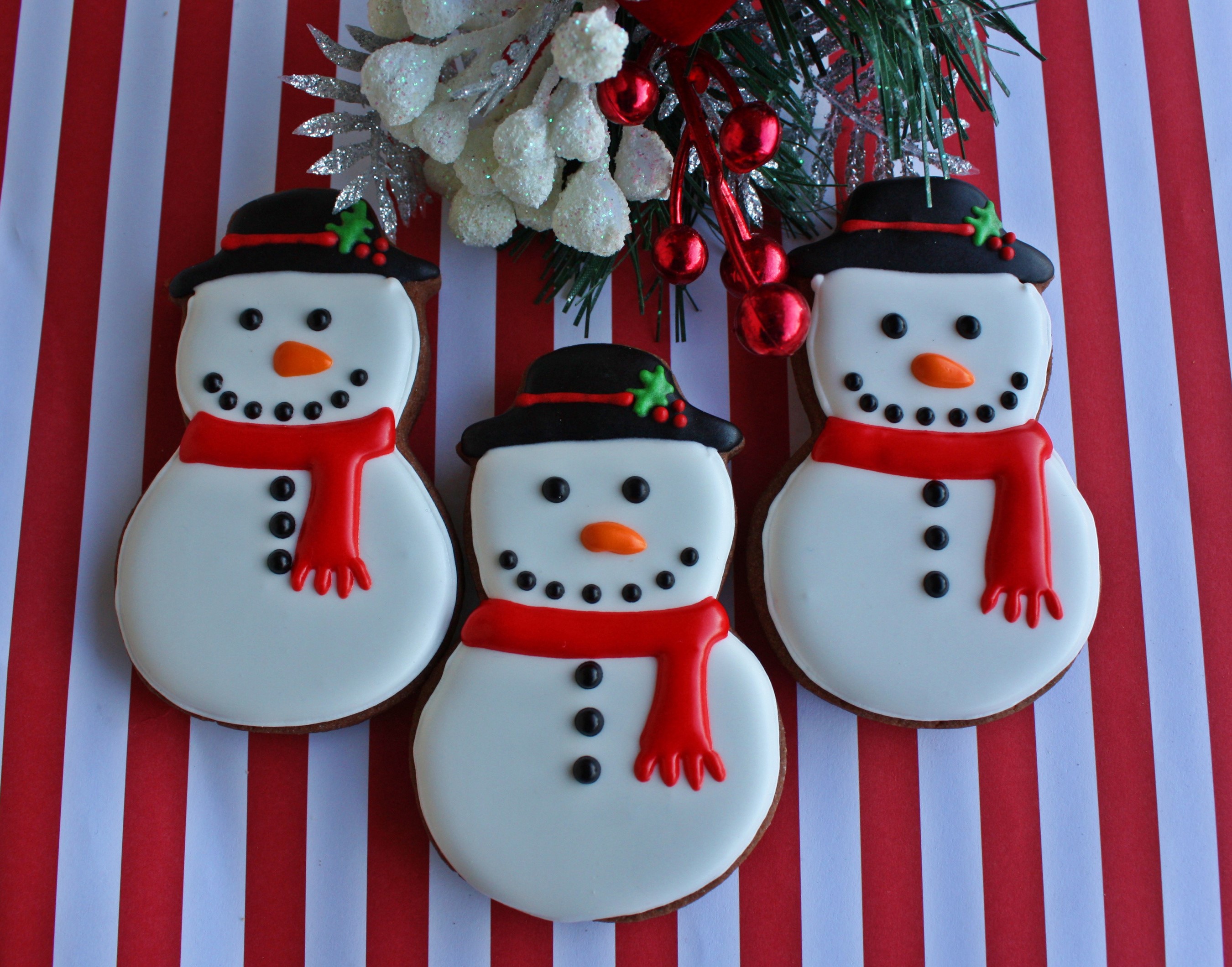 Three Christmas snowman cookies with red and white striped background HD Wallpaper