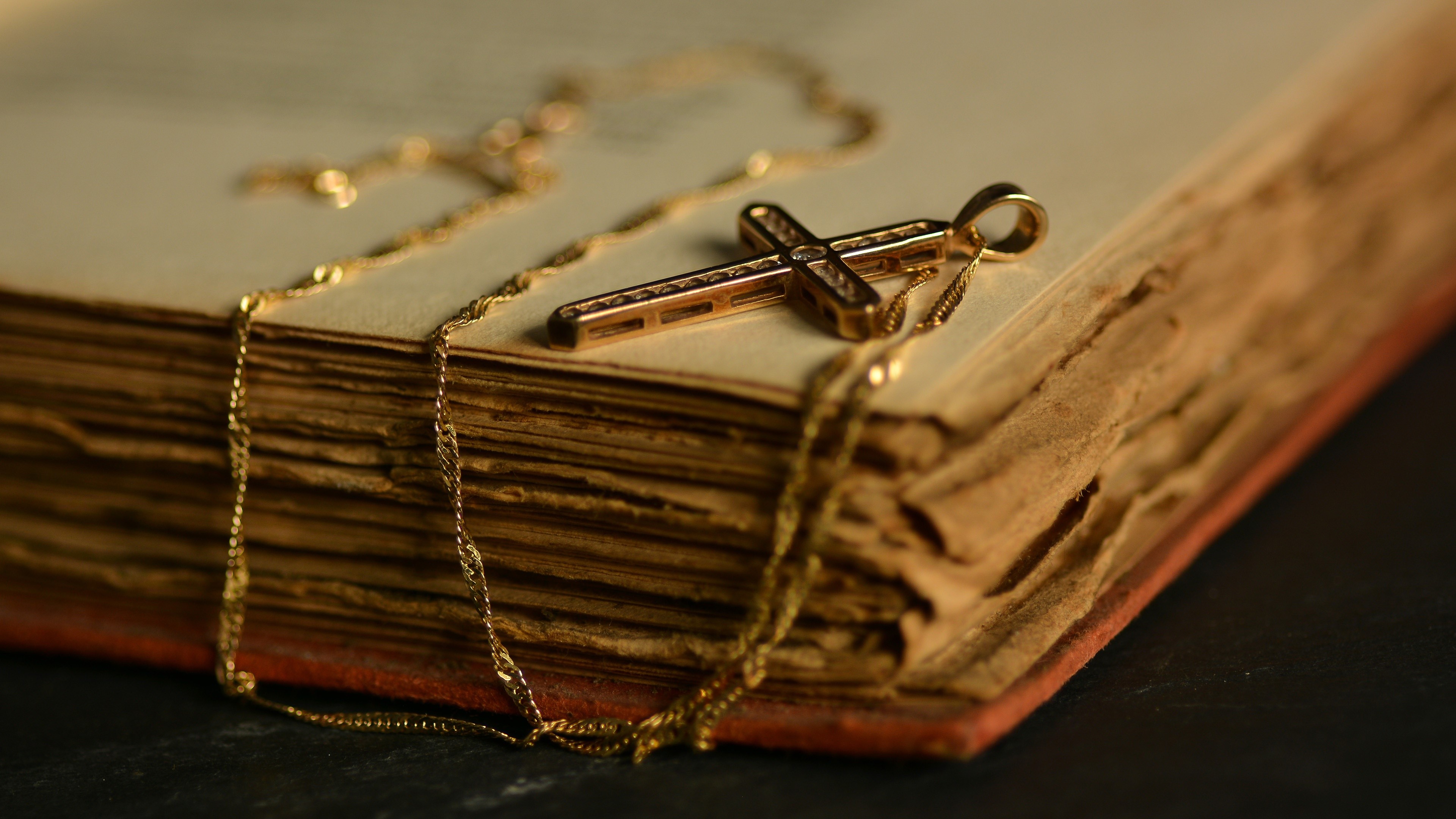 Gold cross necklace on an old book HD Wallpaper