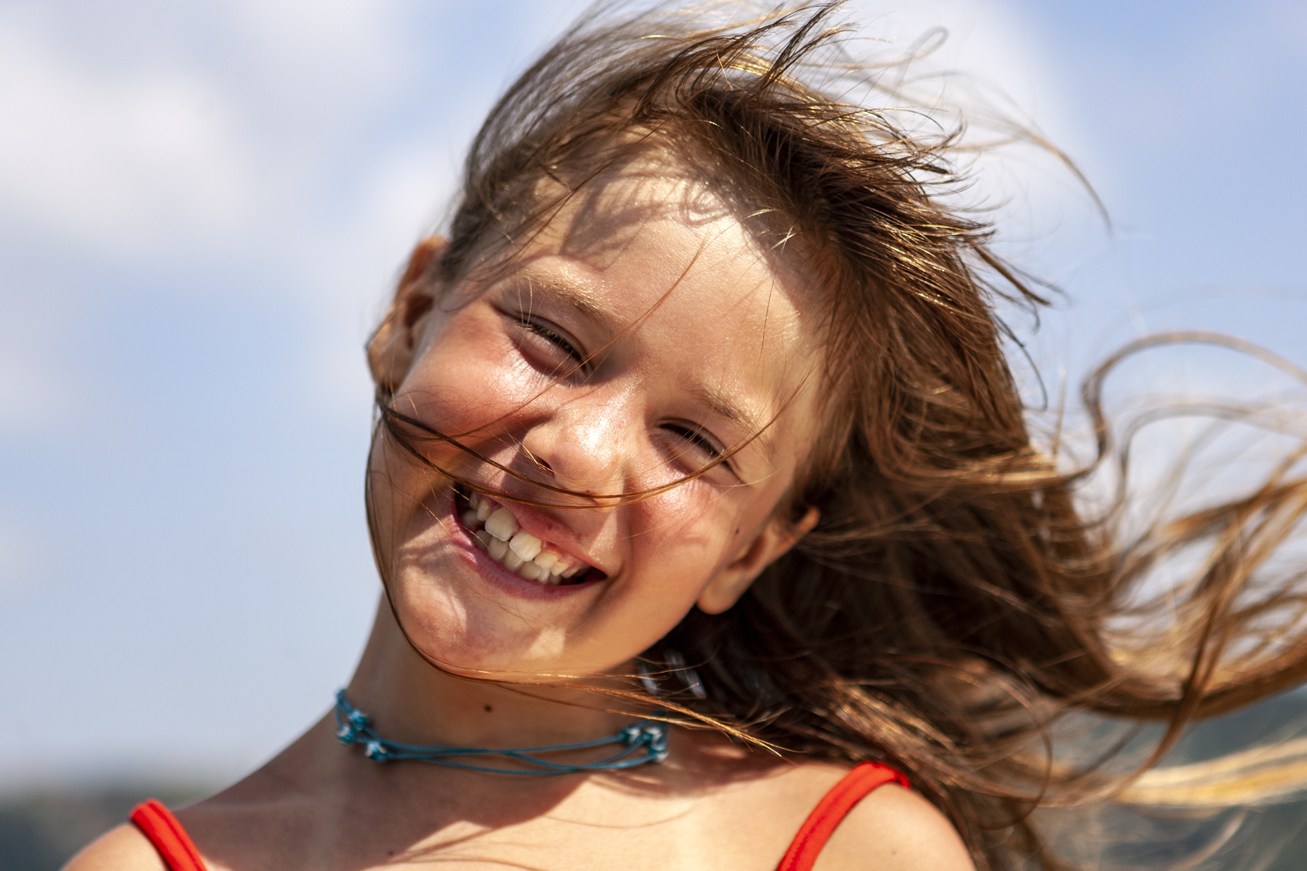 Girl with windblown brown hair smiling HD Wallpaper